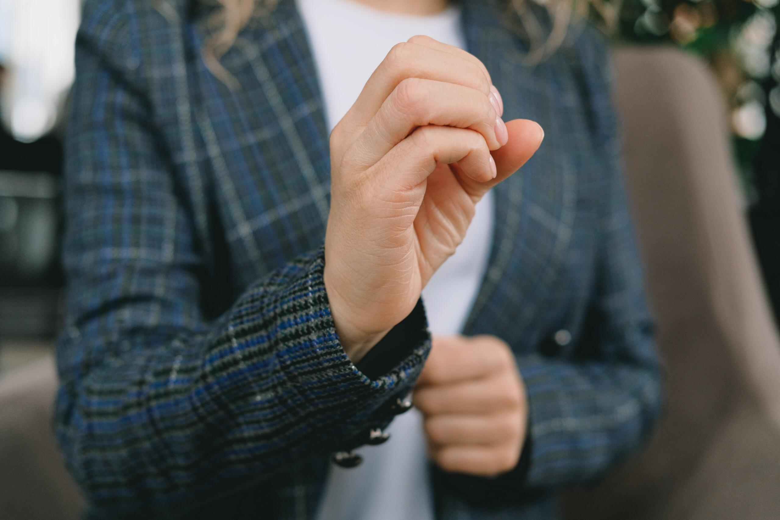 woman making sign language gesture with hand clenched into open fist
