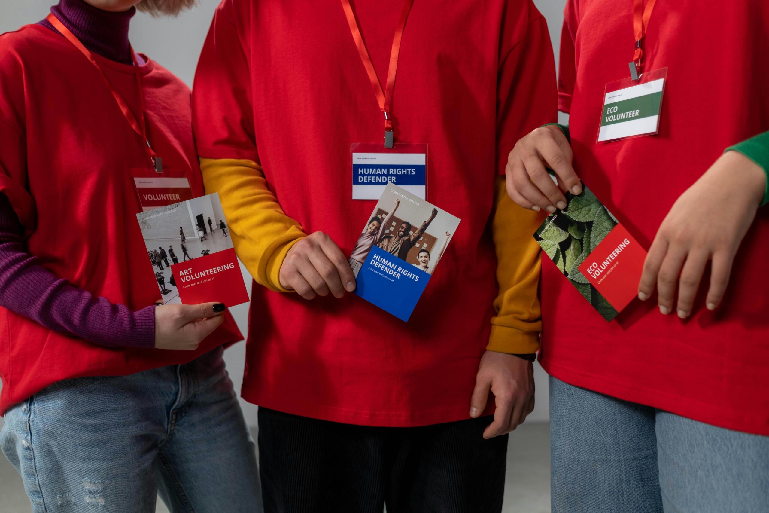 three students standing side-by-side showing their volunteer badges