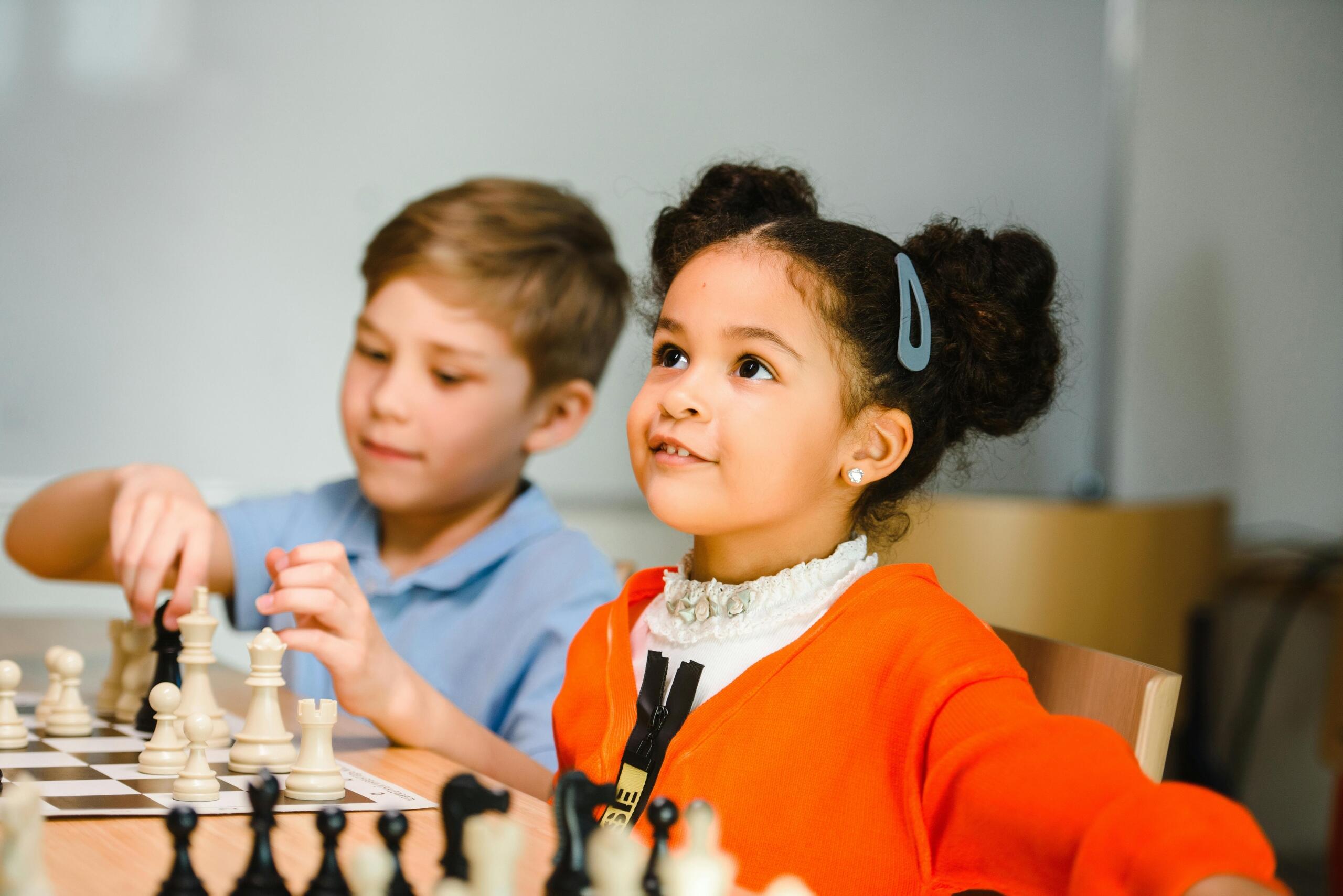 two preschoolers sitting side by side playing chess