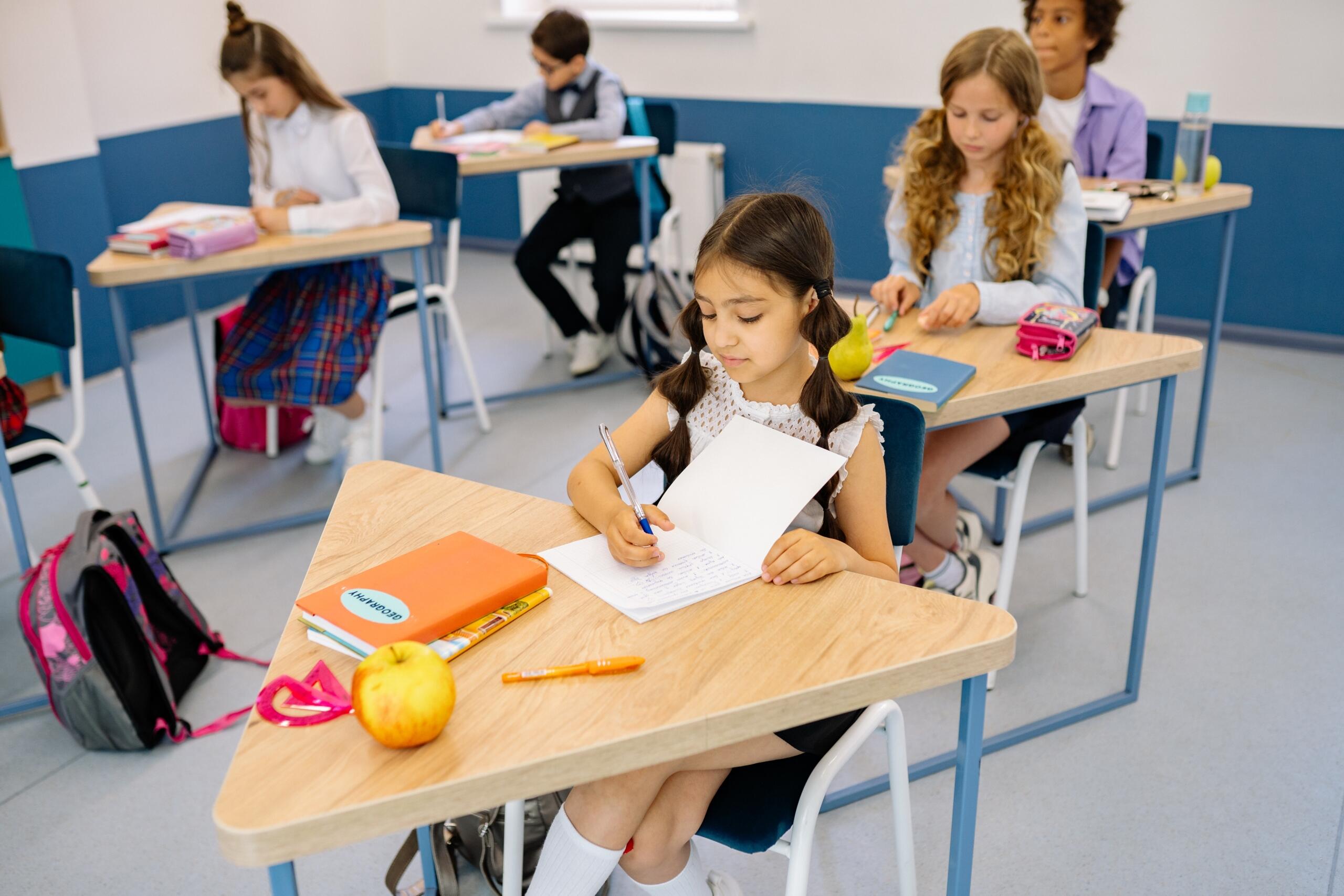 students sitting at tables in classroom taking notes