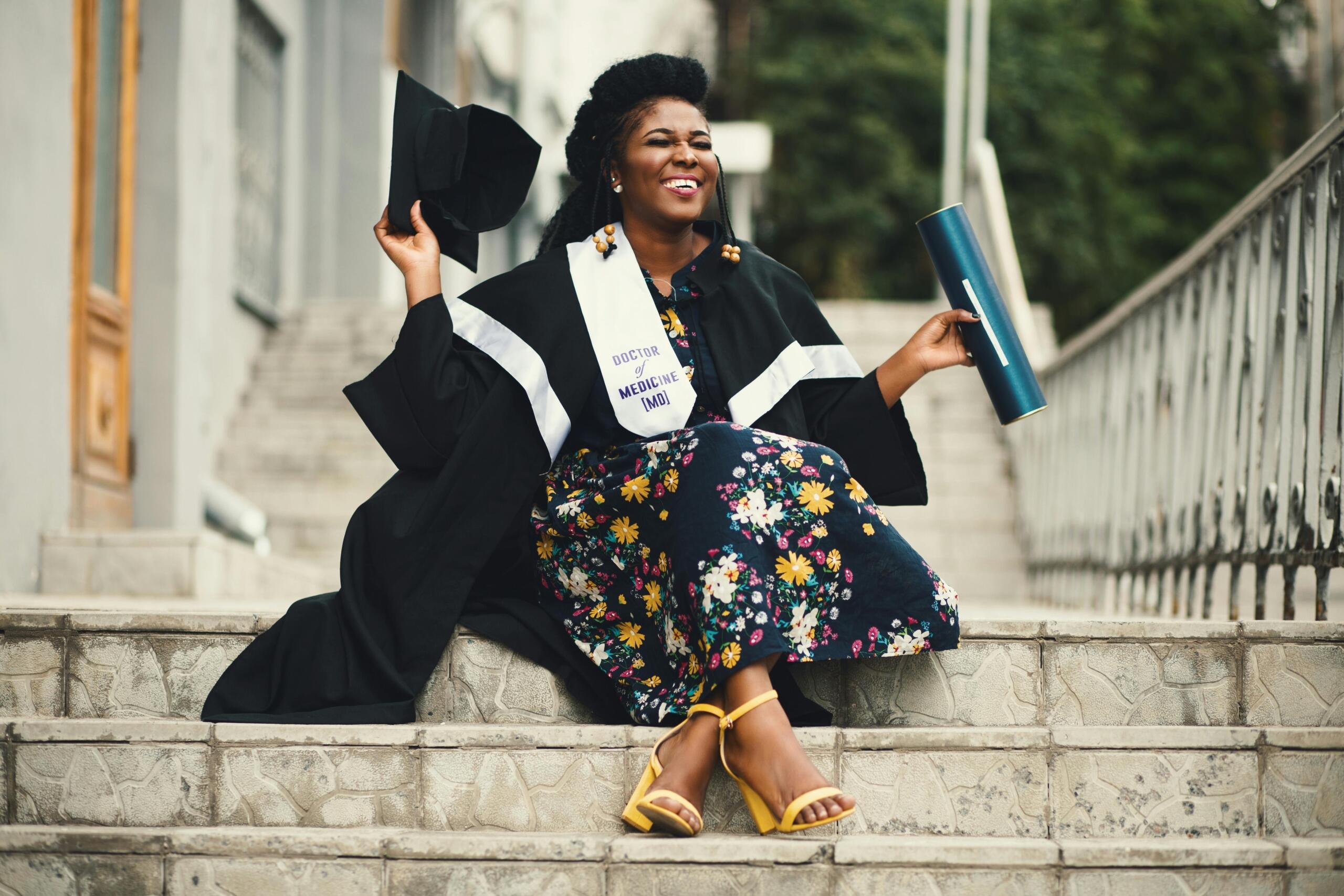 smiling medical school graduate wearing graduation gown and holding mortarboard