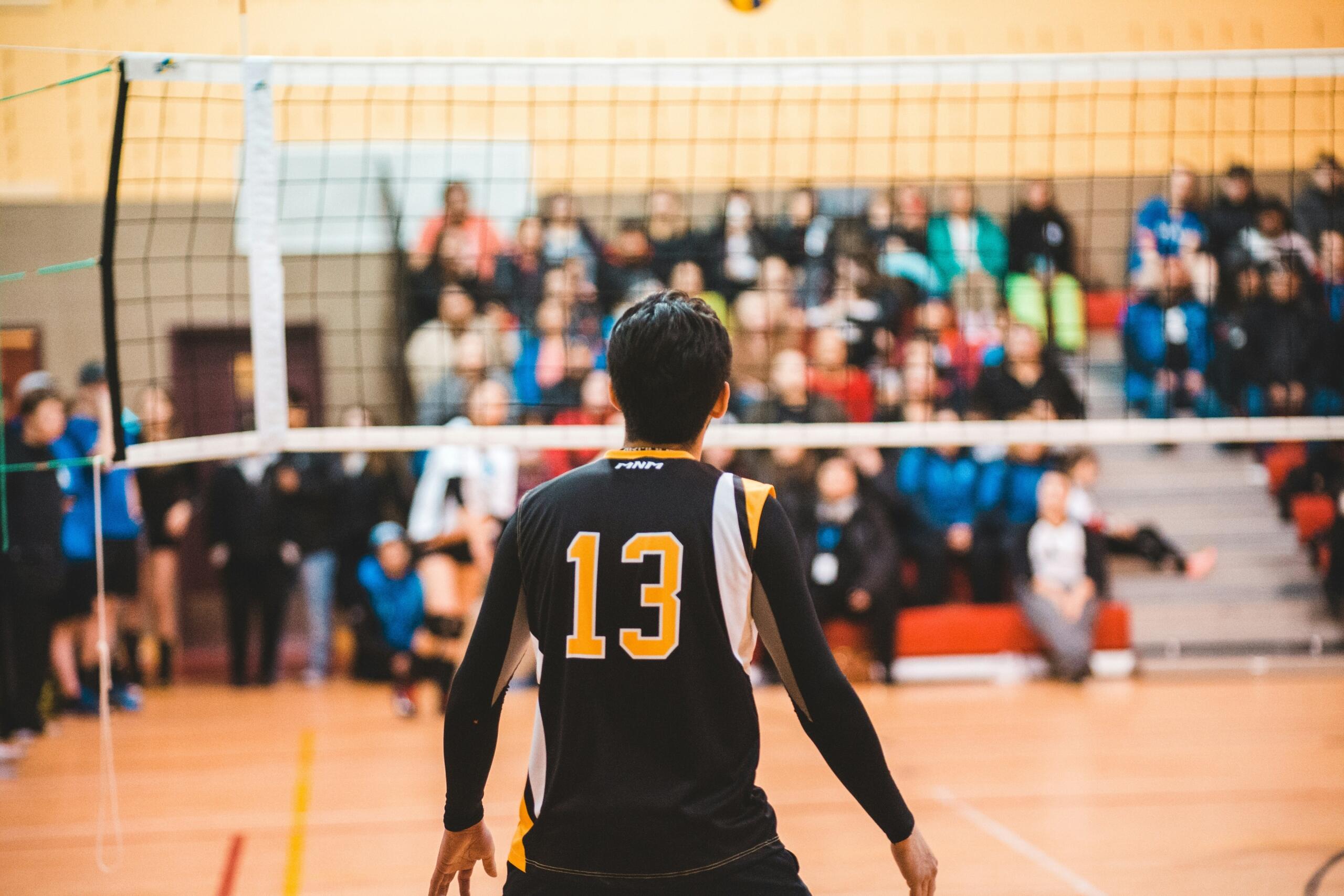 A volleyball player facing the net with a number 13 kit