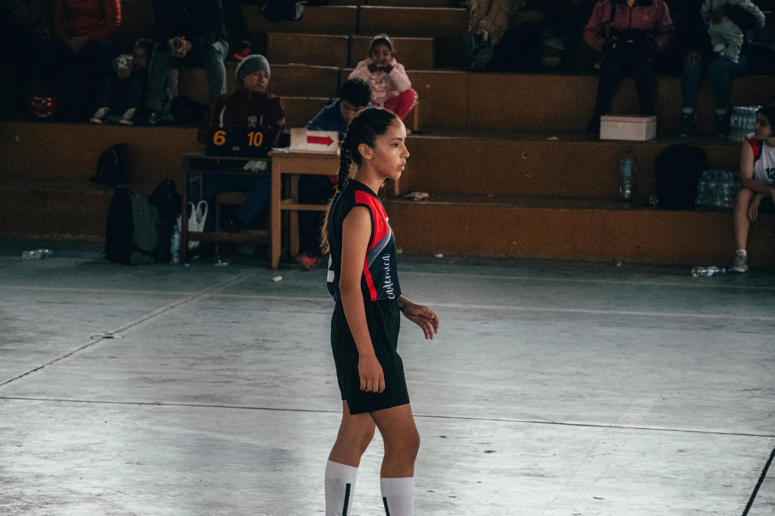 A volleyball player standing in an indoor volleyball court