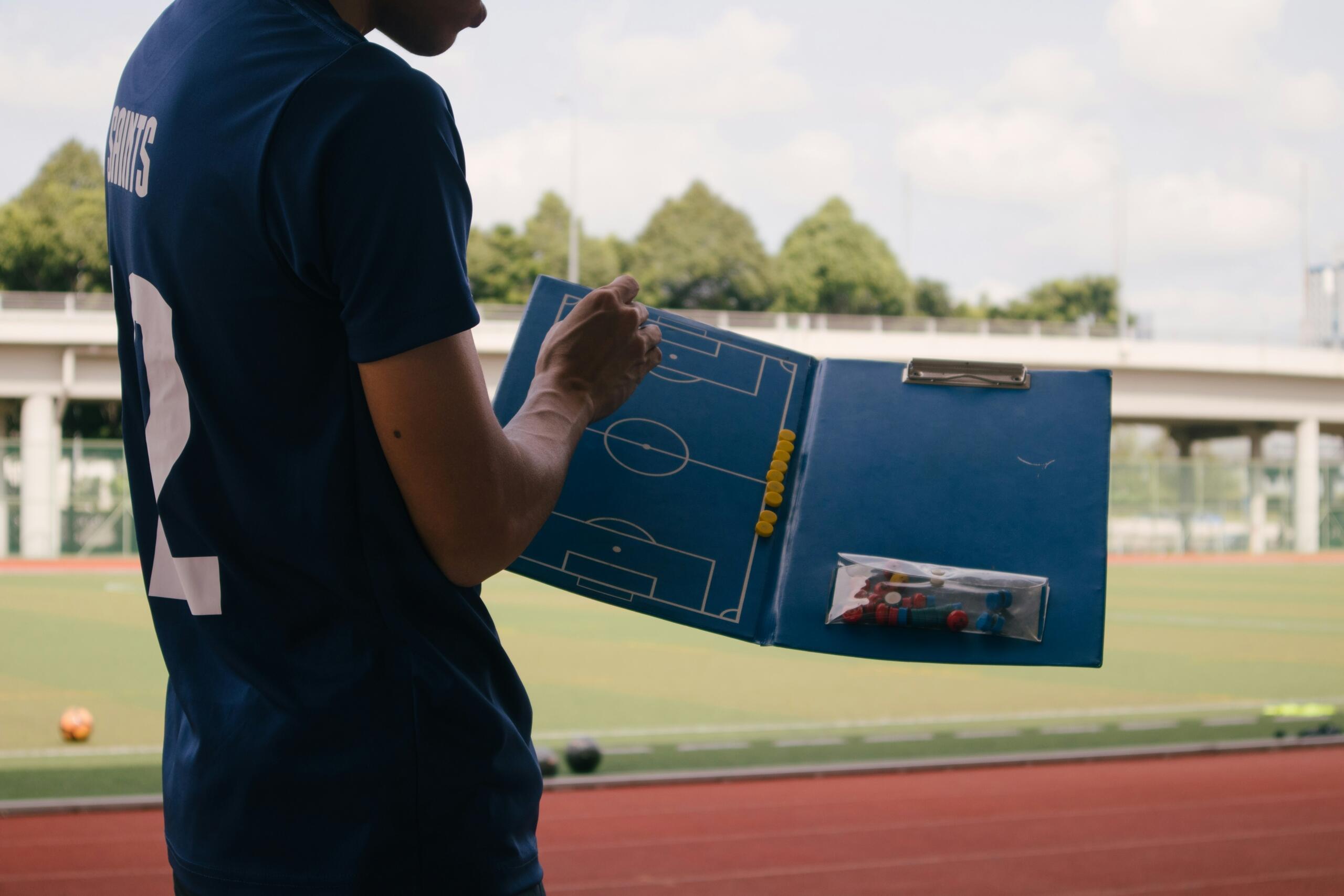 Coach guiding with a clipboard picture depicting the volleyball court