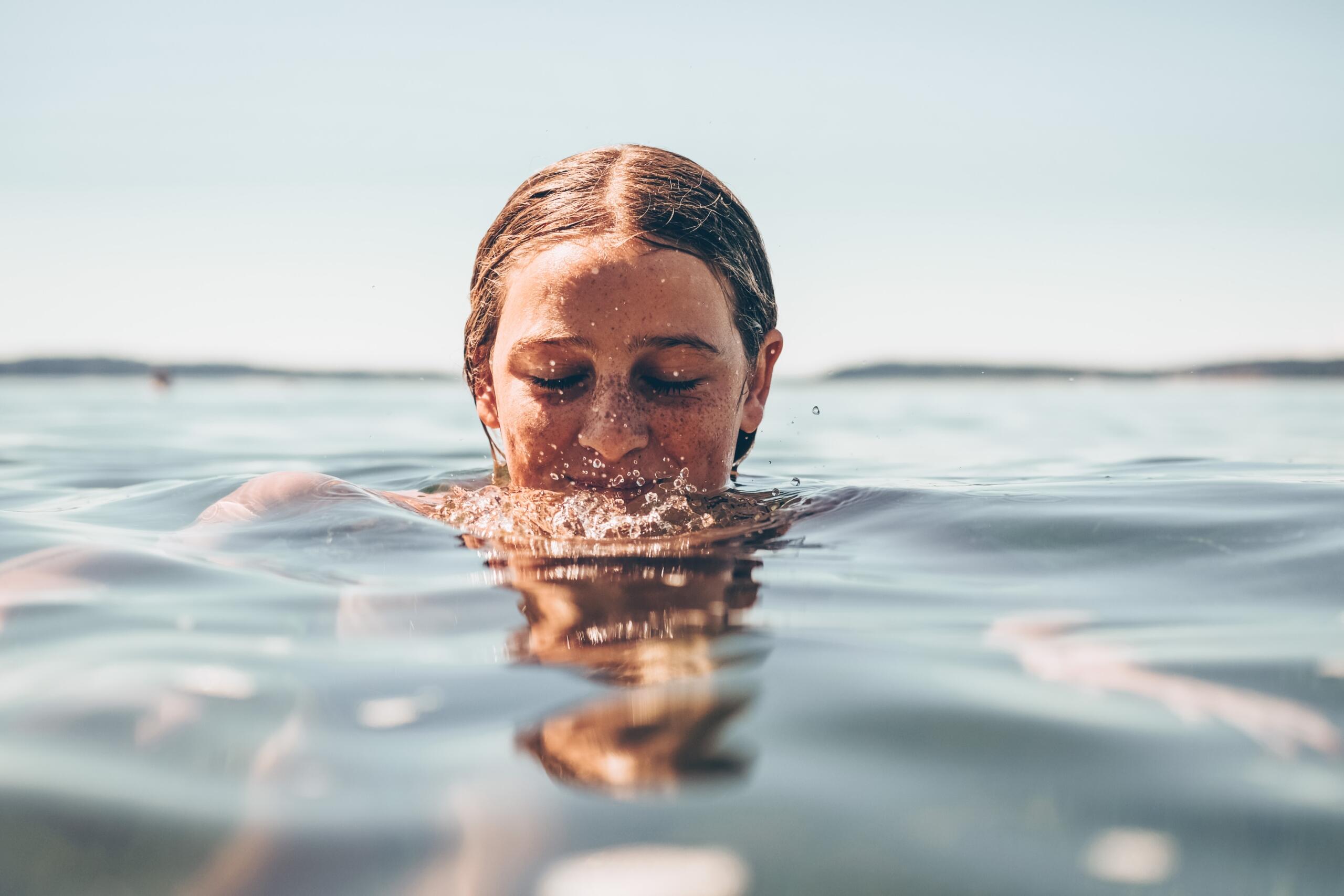 person treading water in open body of water under sunny skies