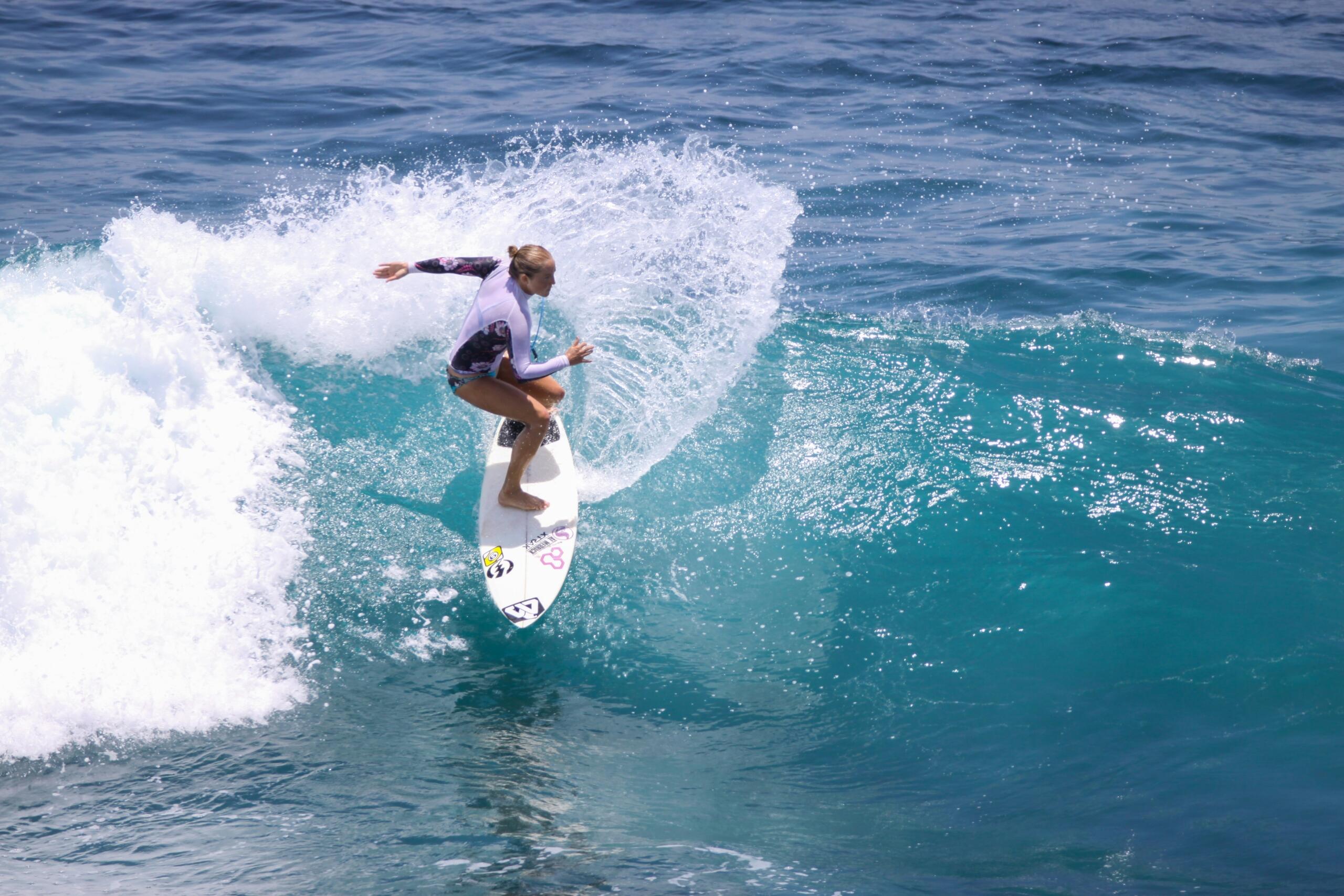 woman in springsuit on white surf board surfing in the ocean