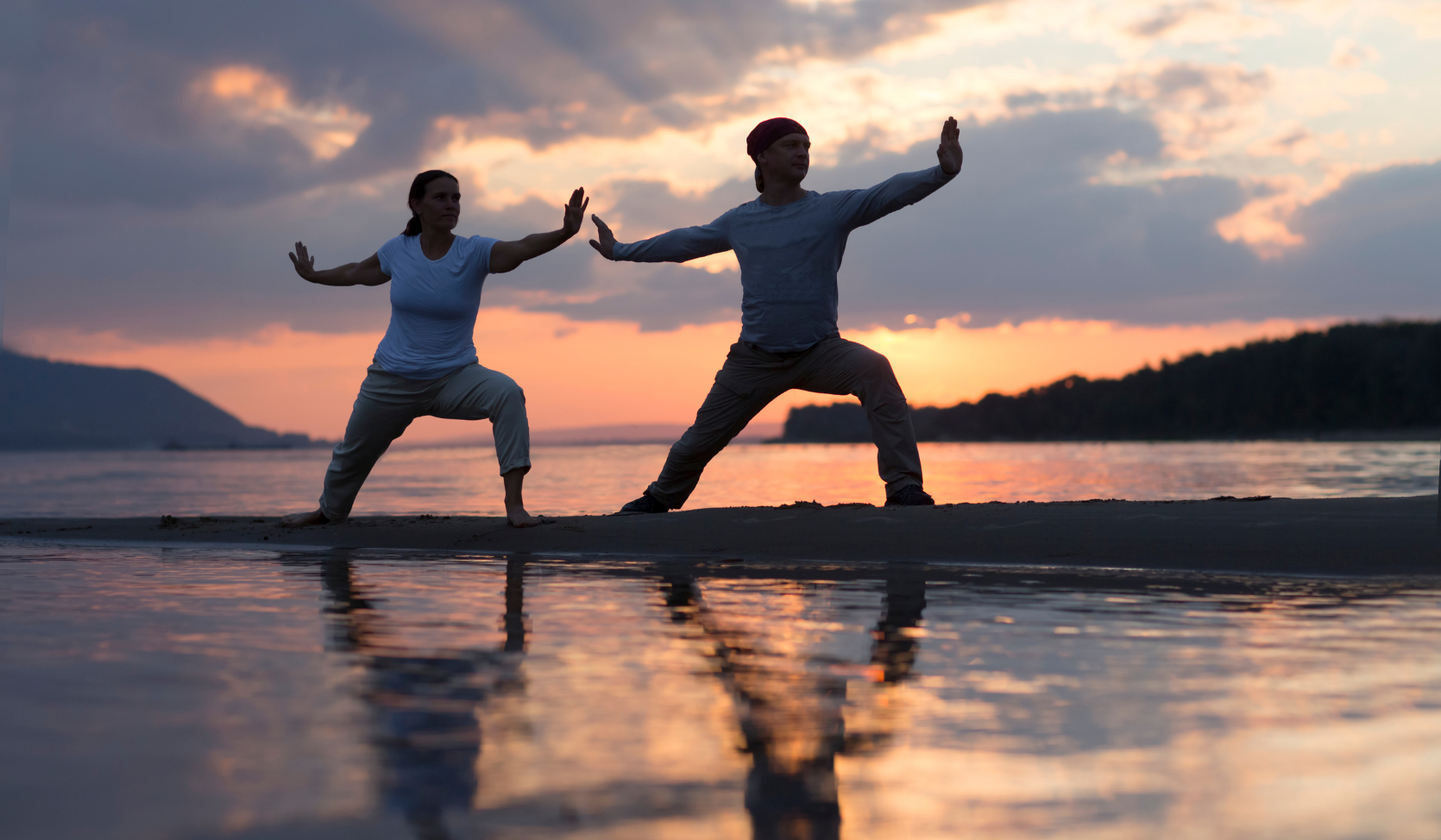 An image of two people practising Tai Chi against a sunset