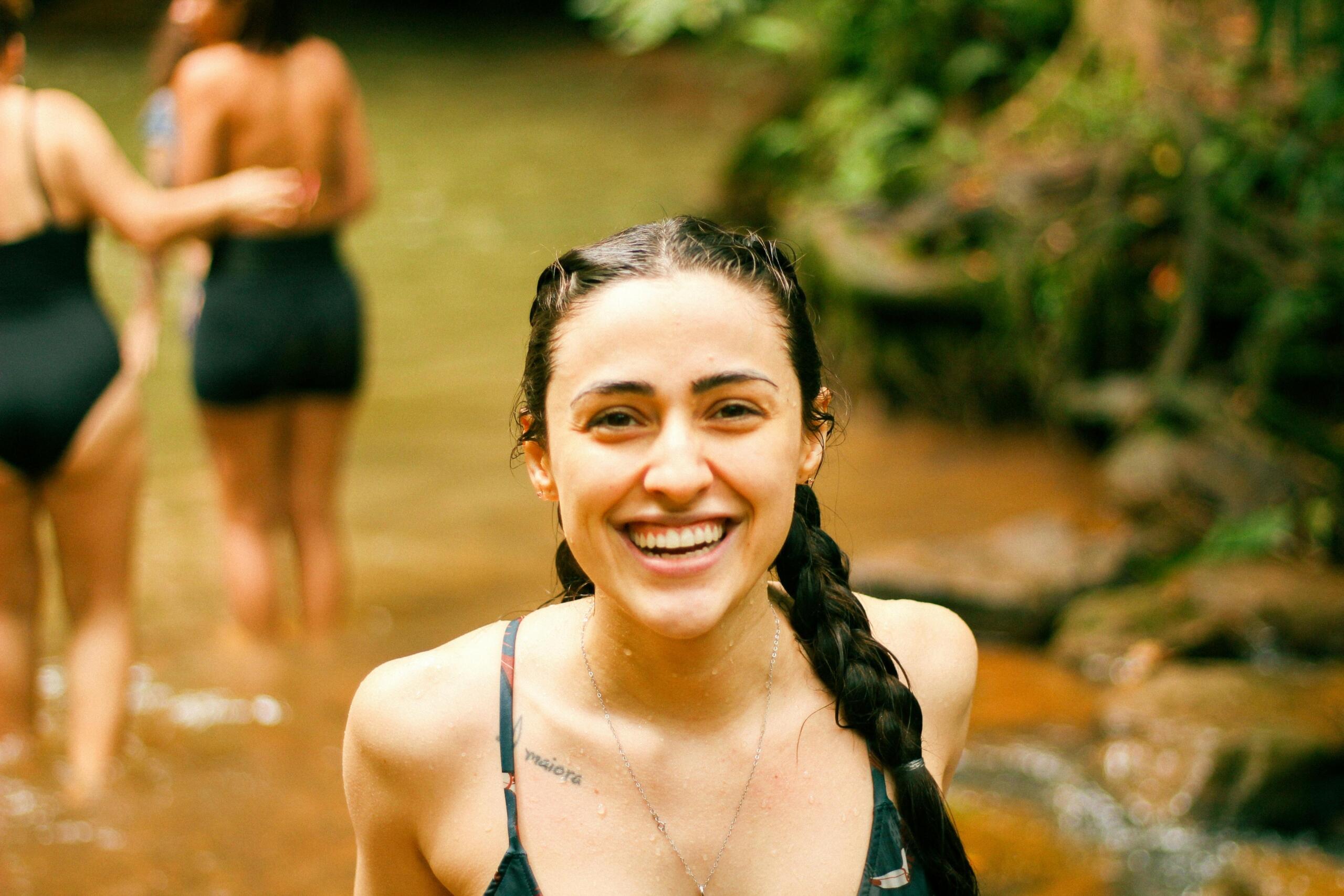 smiling woman standing in a river with people in the background