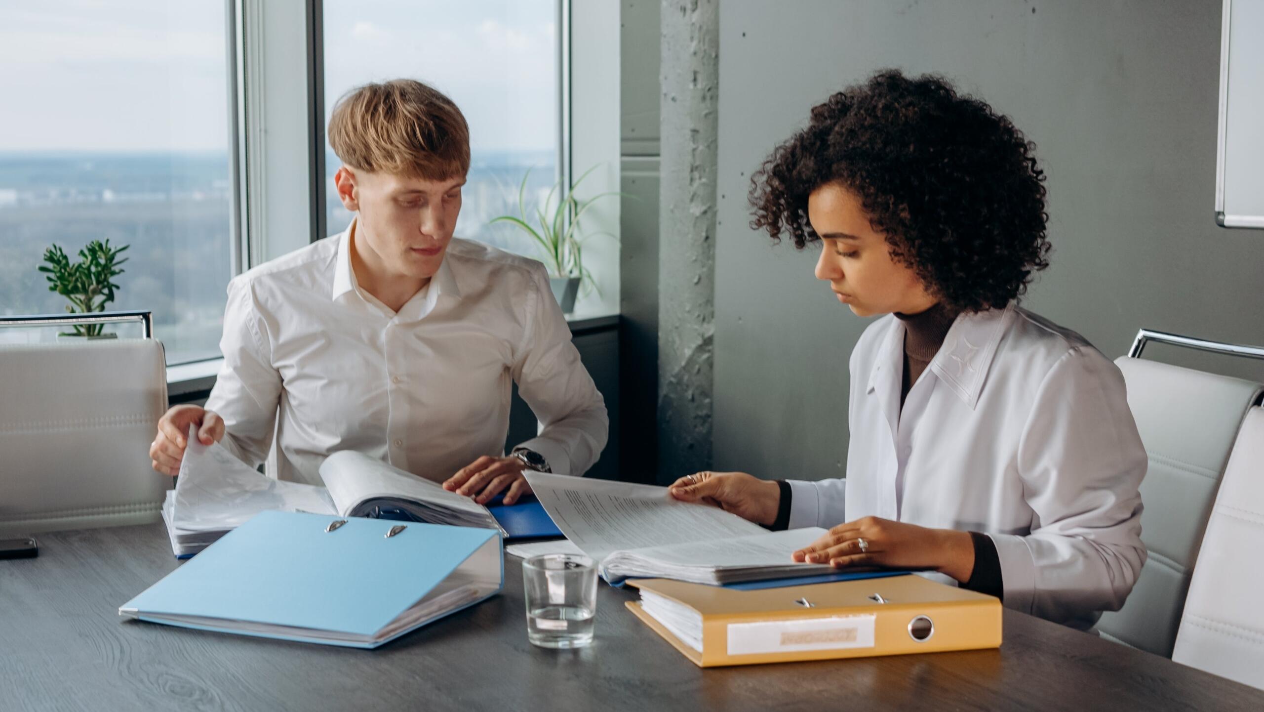 two accountants sitting at a table looking through files