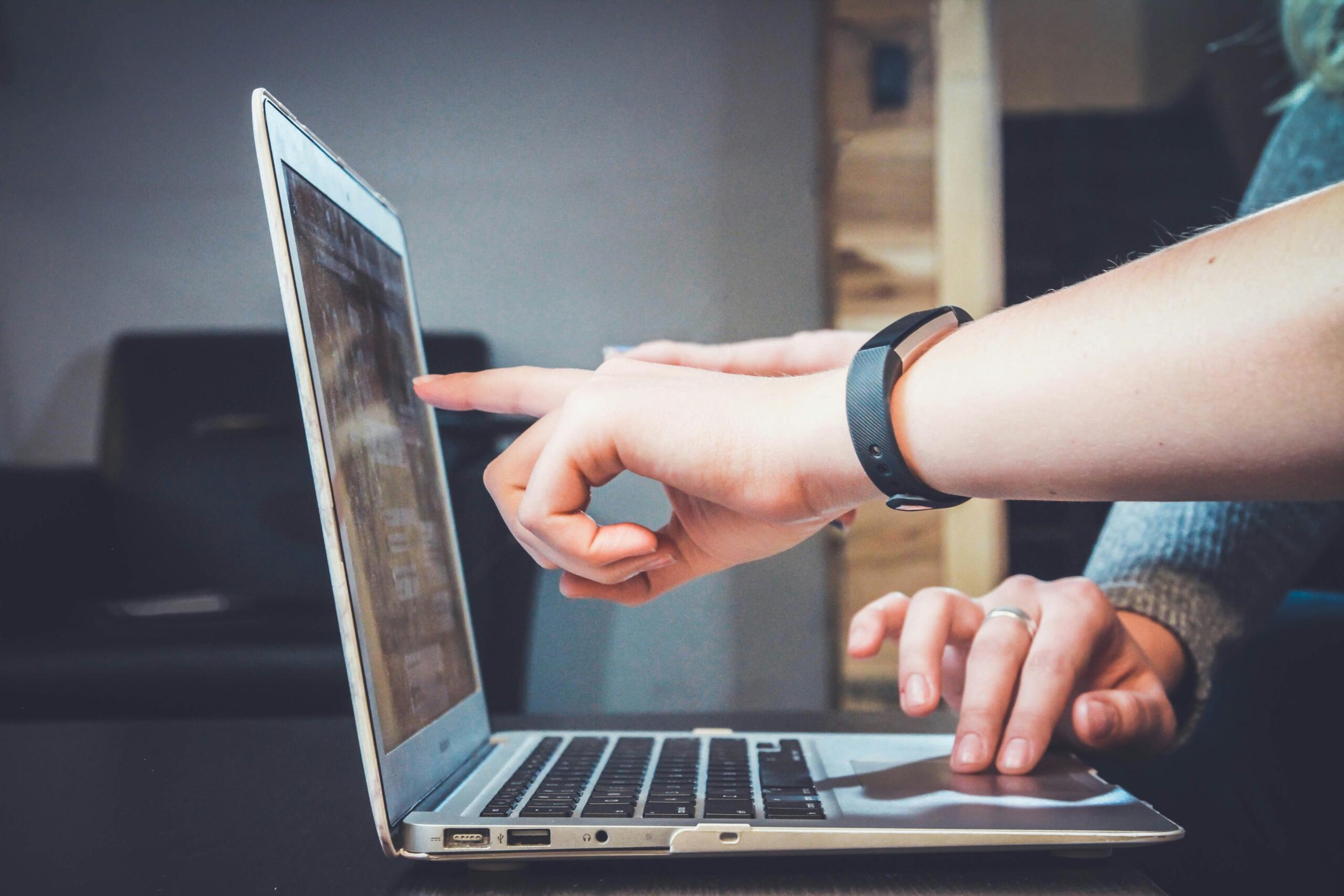 An image of hands pointing to something on a computer screen. 