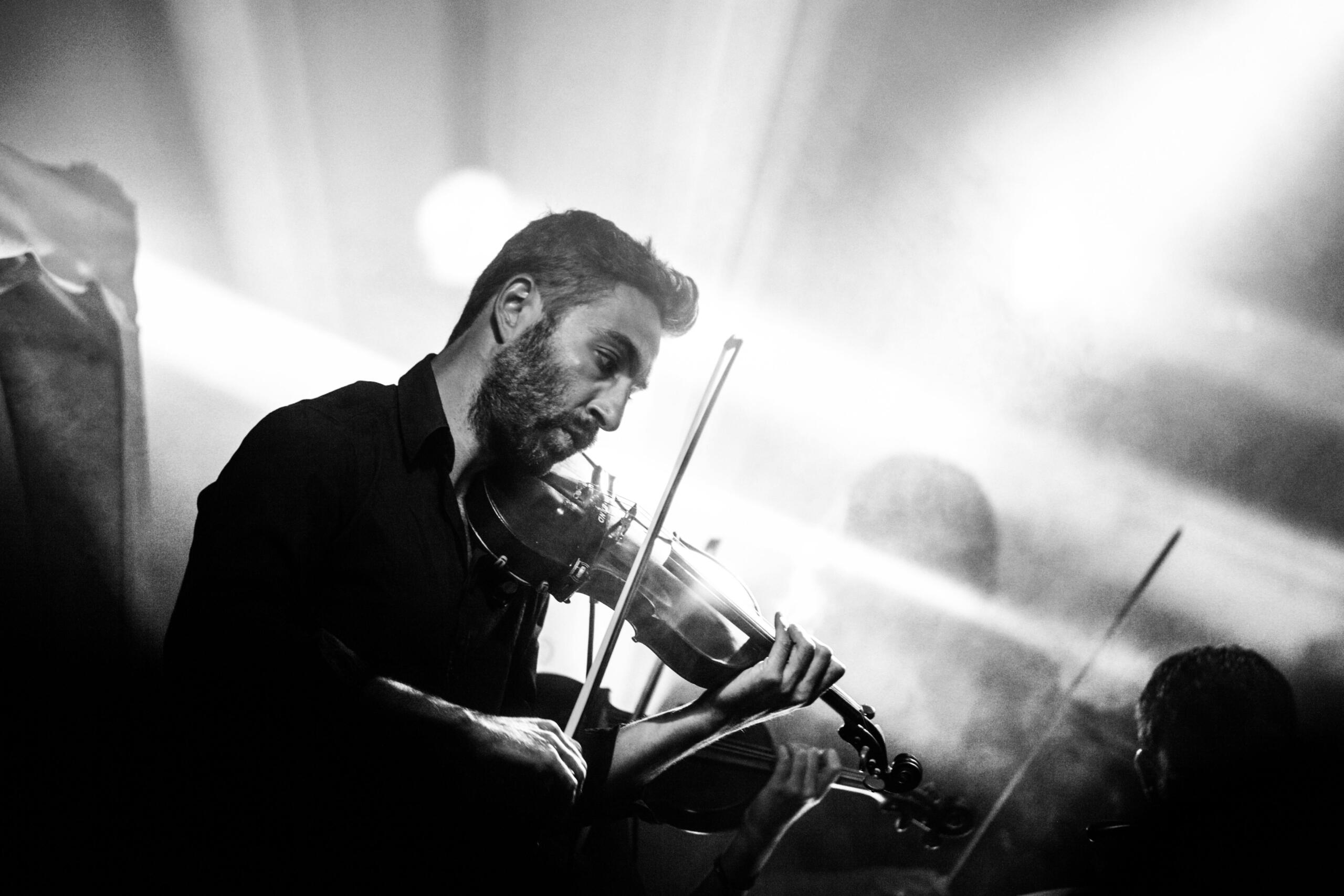 A black and white image of a violin player in concert. 