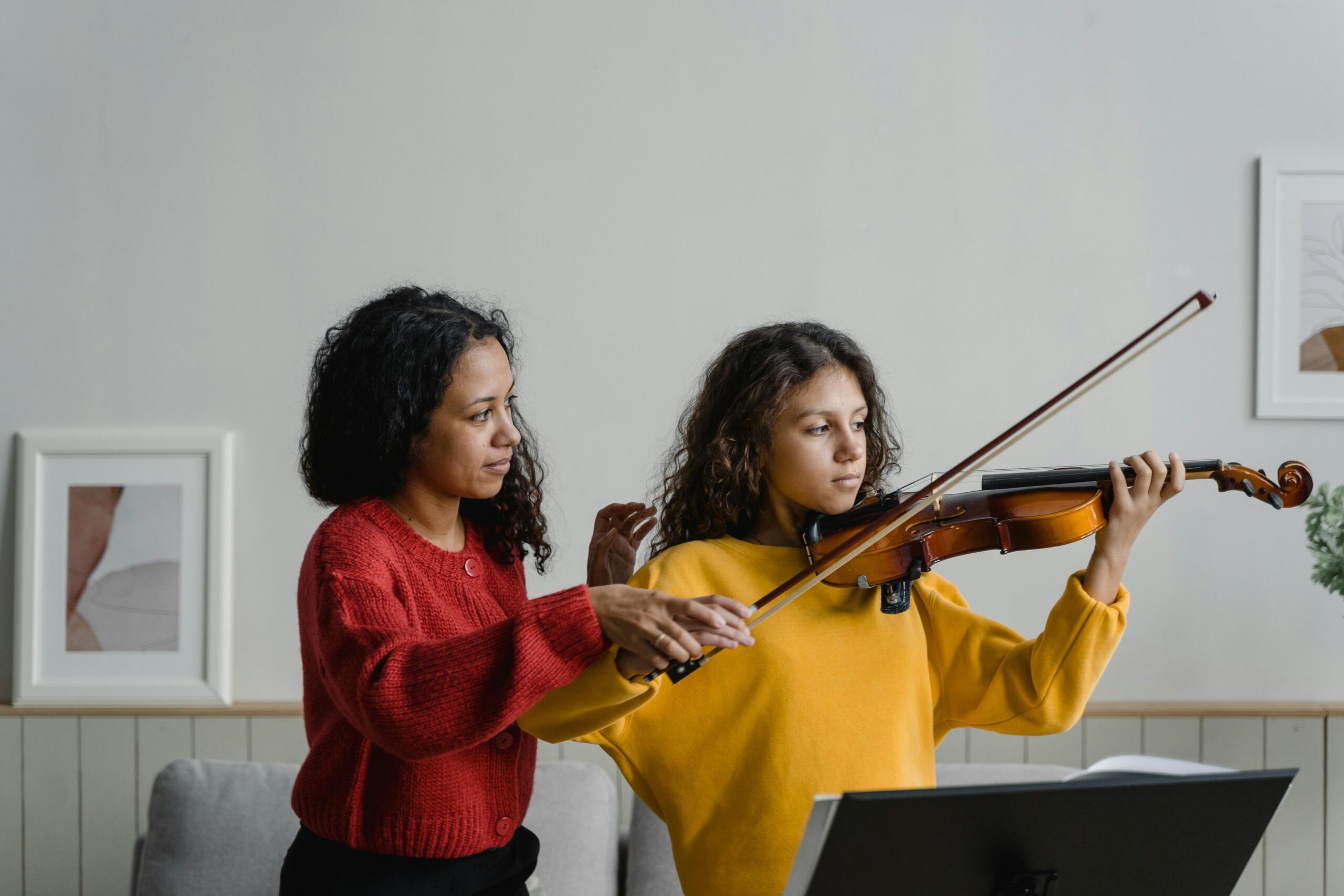 teacher helping student play the violin