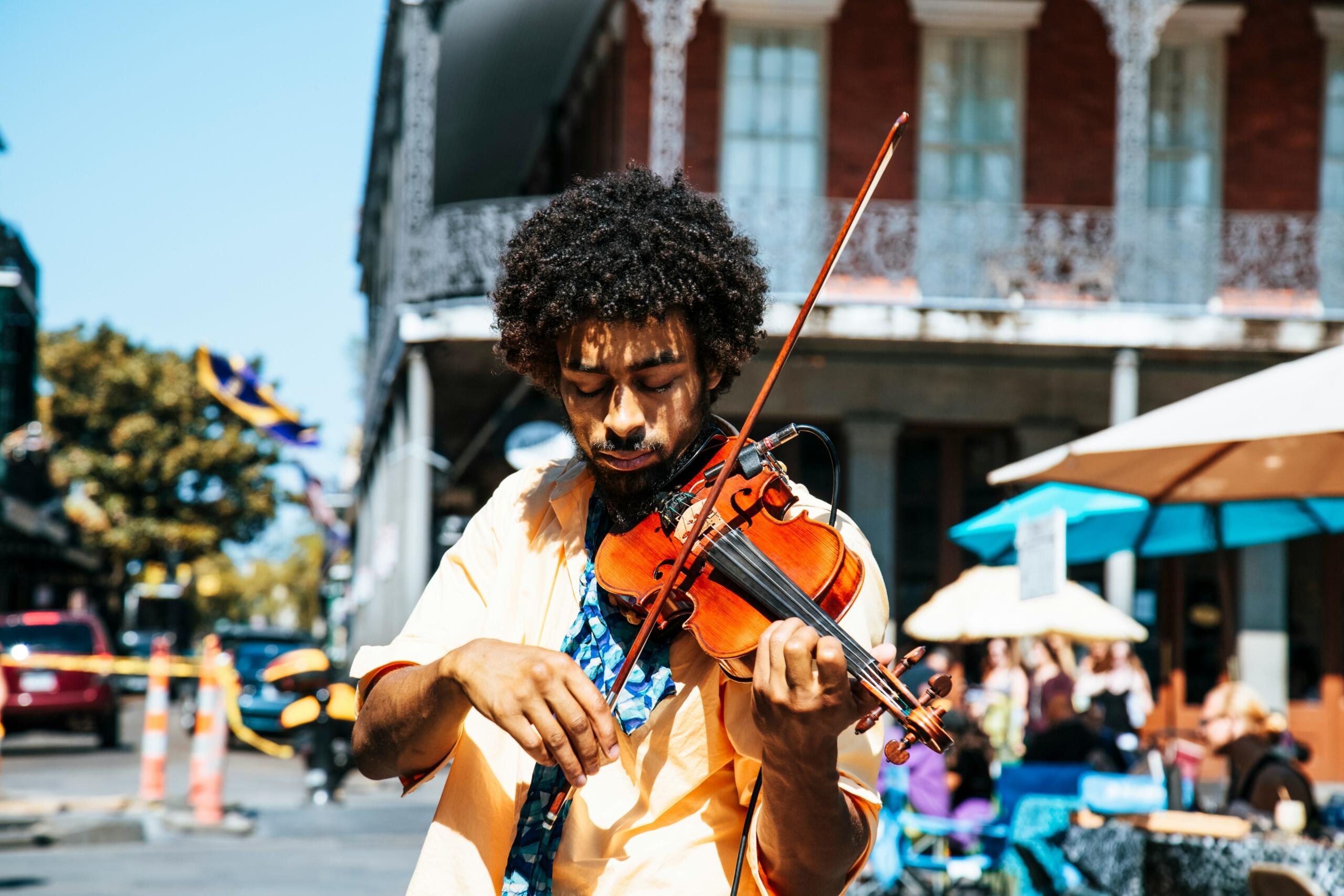 man playing the violin in the street near a cafe