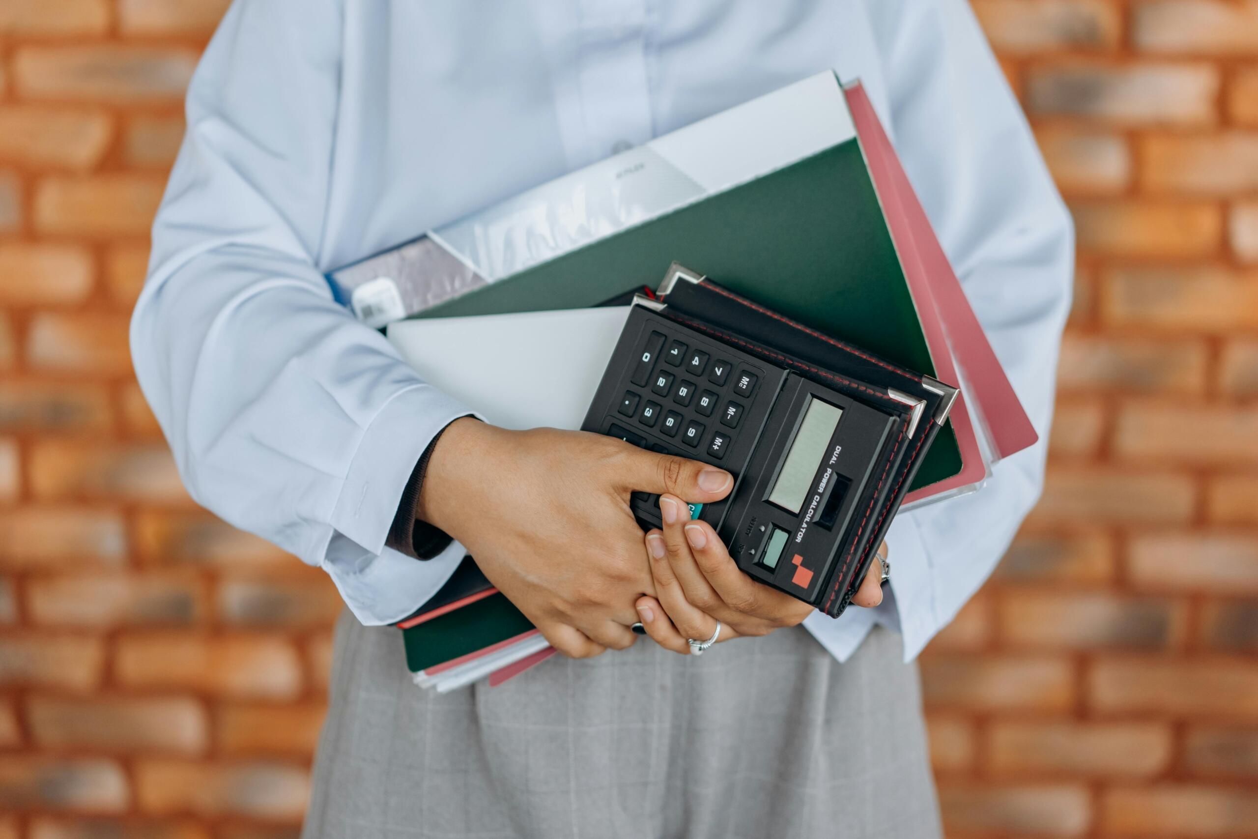 a student in a school uniform holding notebooks and a calculator