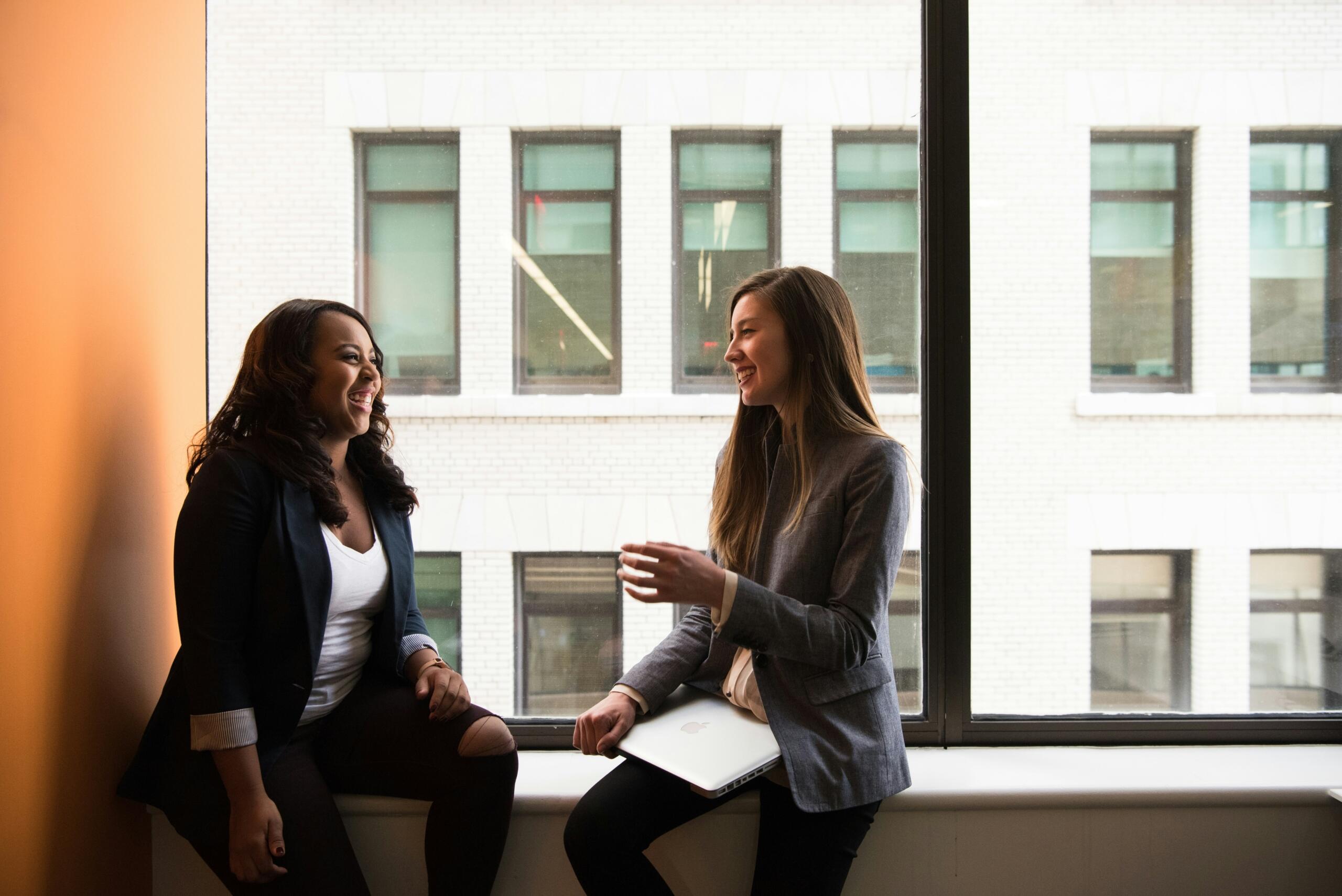 An image of two women talking in a business setting. 