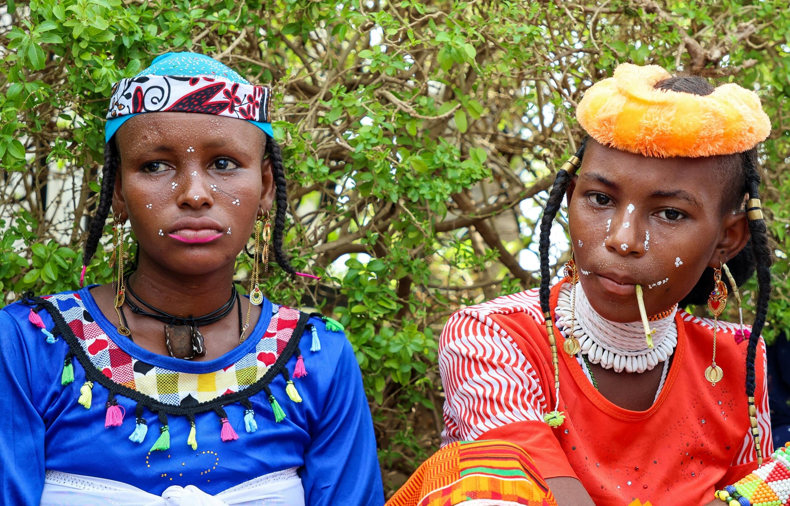Two Zulu ladies in traditonal dress sitting side by side.