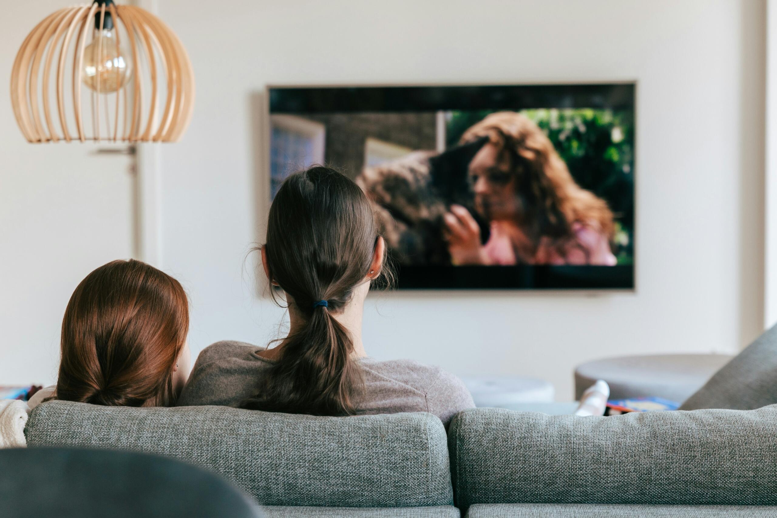 An image of two girls watch a TV show.
