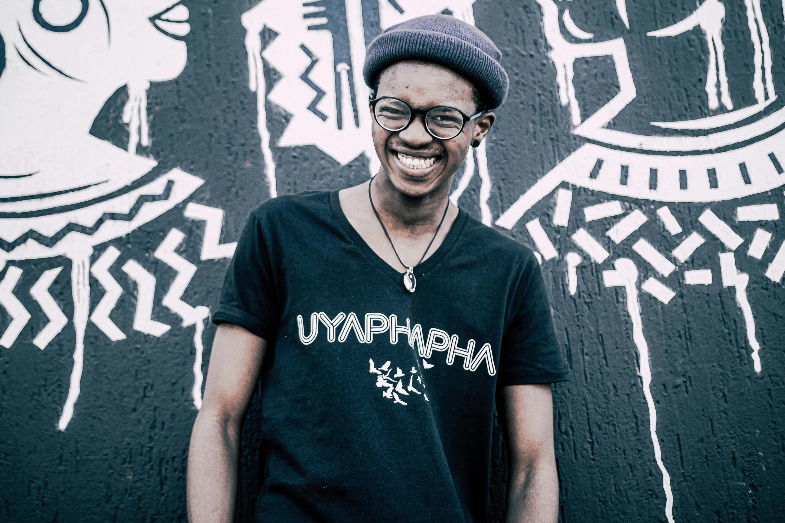 An image of a young South African man against a wall of graffiti.