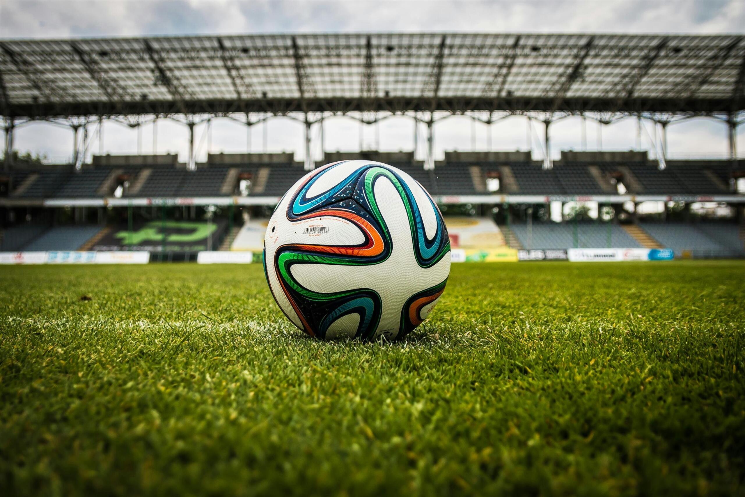 An image of a soccer ball with an empty stadium in the background.