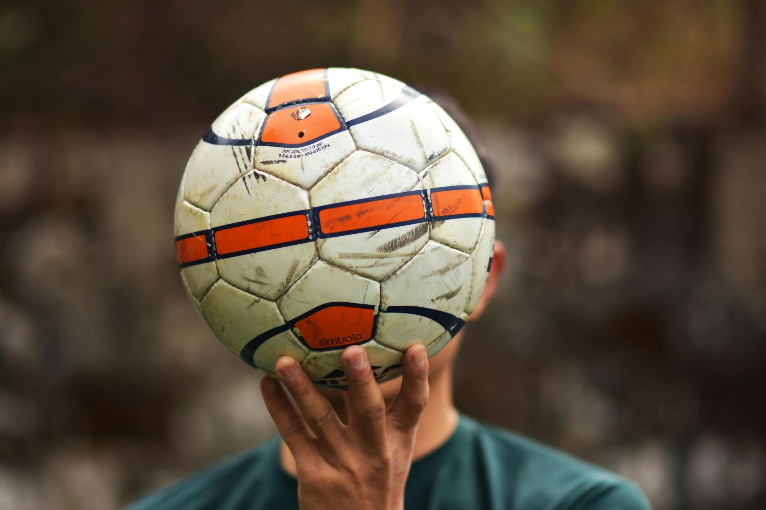 An image of a soccer ball being held in front of a face.