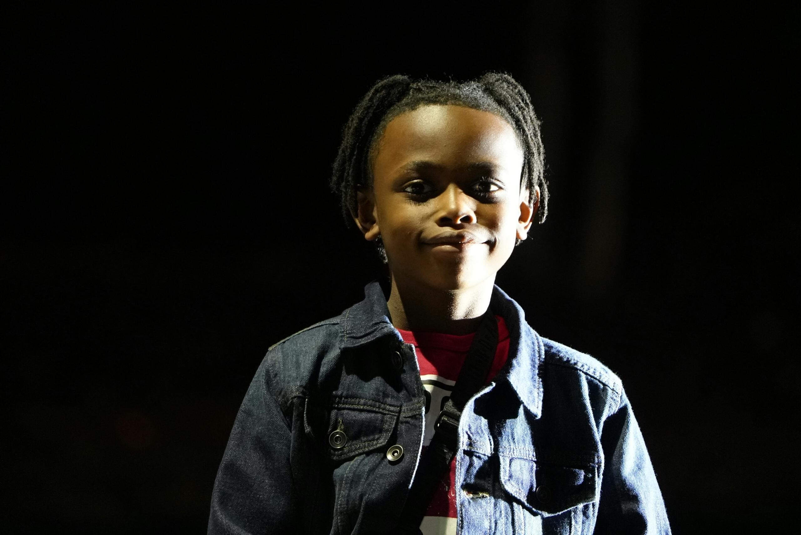 An image of a child against a black background with stage lighting.