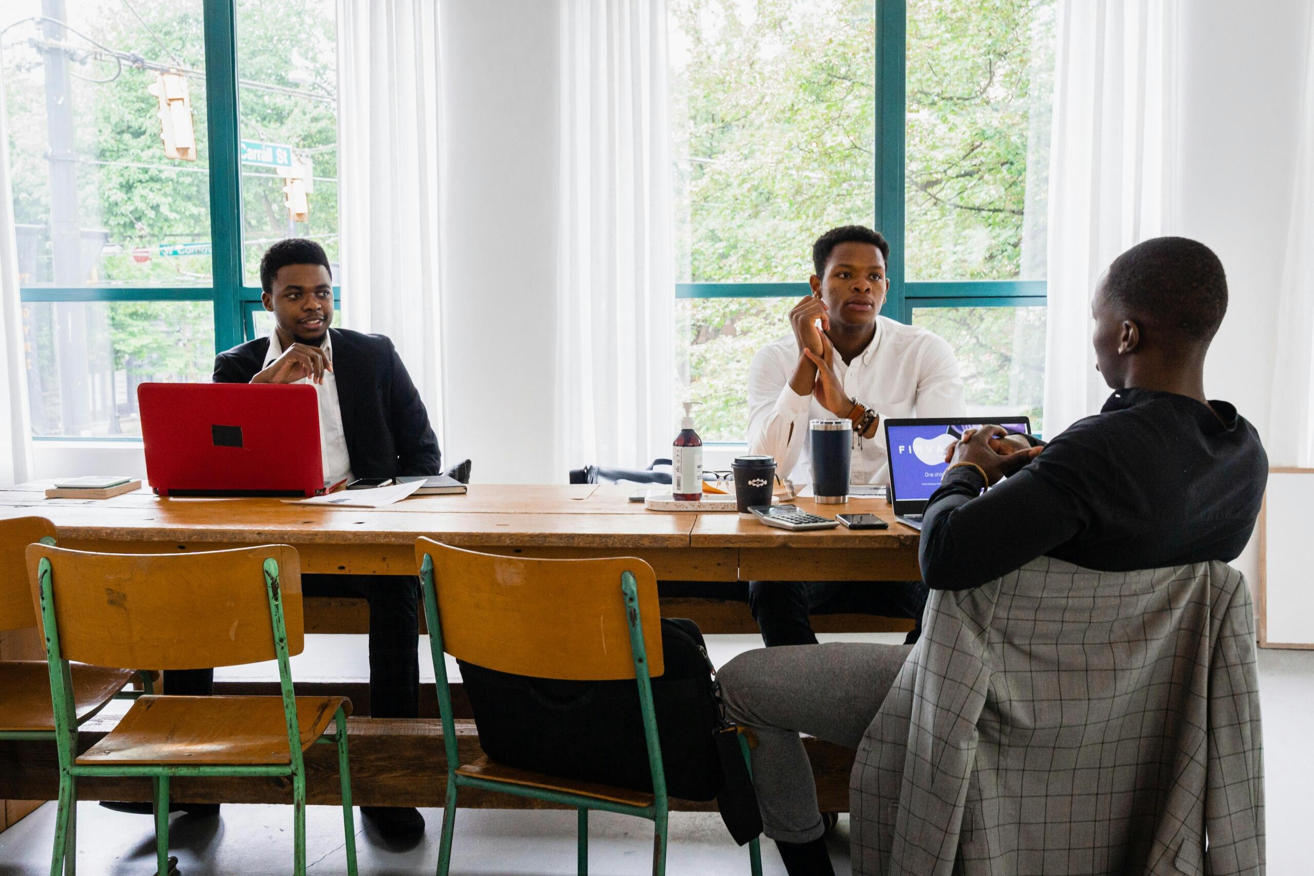 three men sitting around a boardroom table