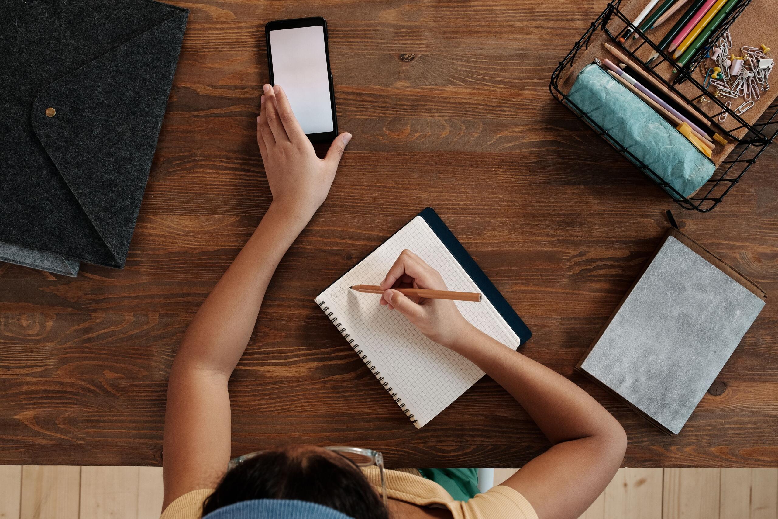 child sitting at a desk using a smartphone to do homework