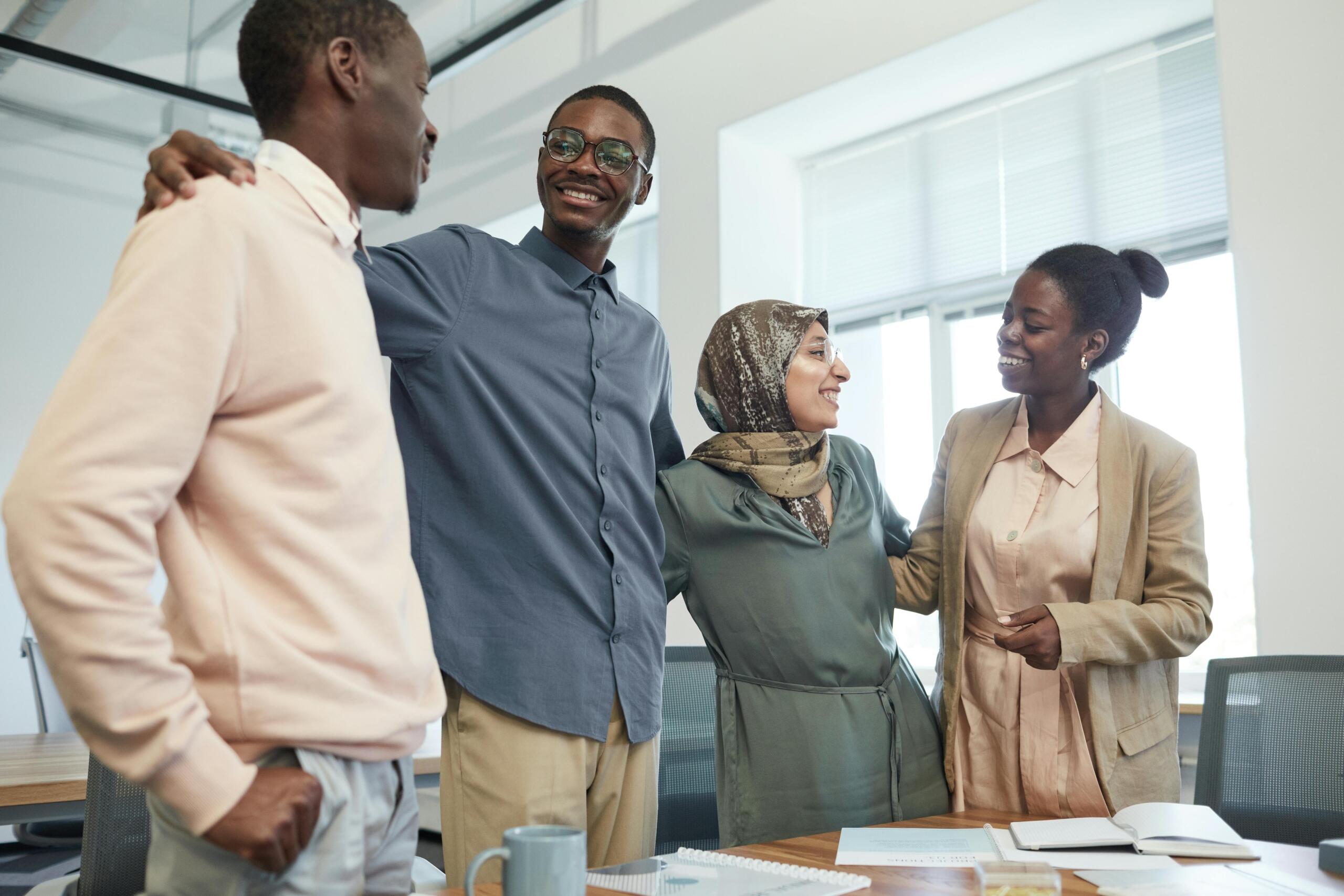 a smiling group of co-workers standing side by behind a desk
