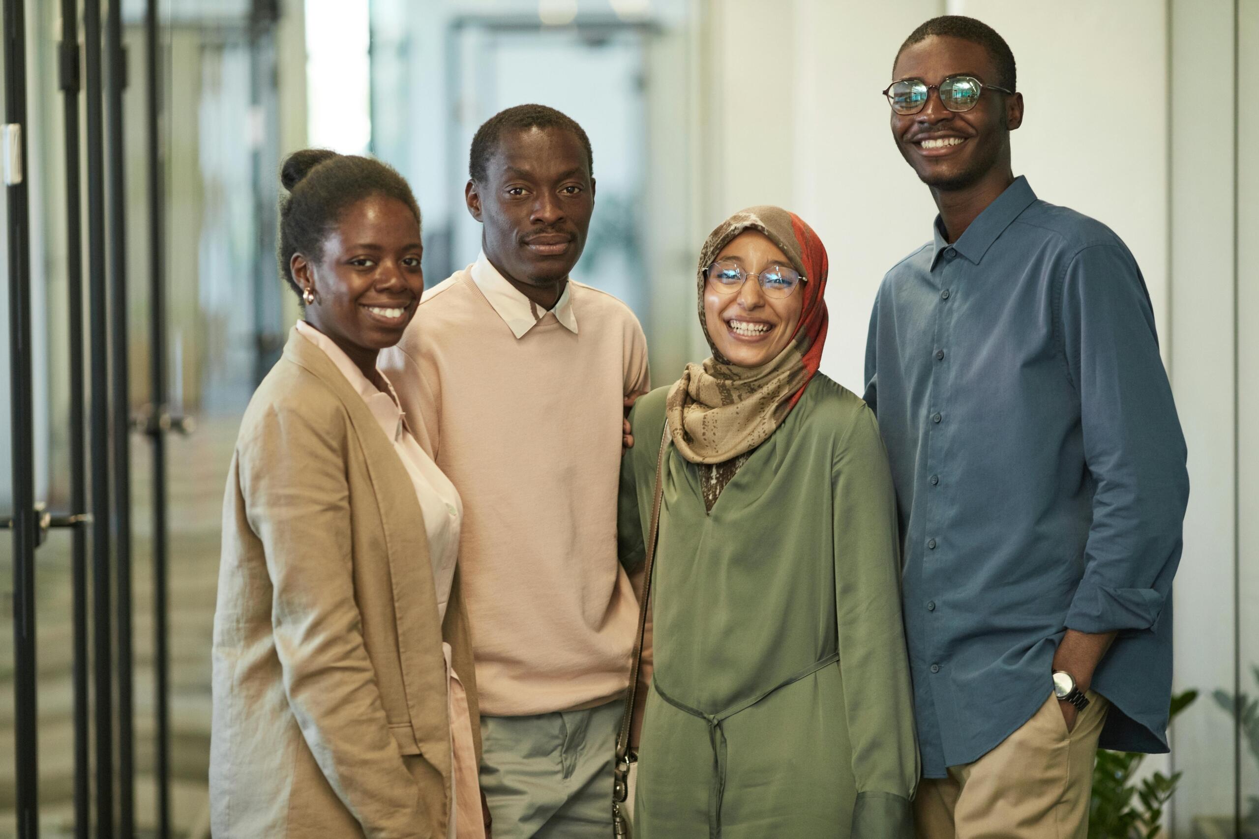 a smiling group of co-workers standing side by side in a corridor