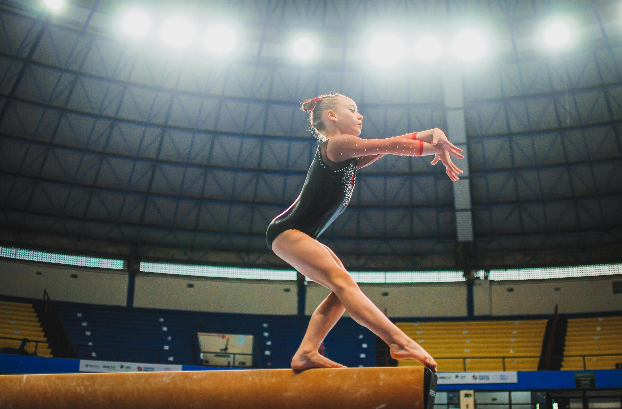 young gymnist walking on a balance beam