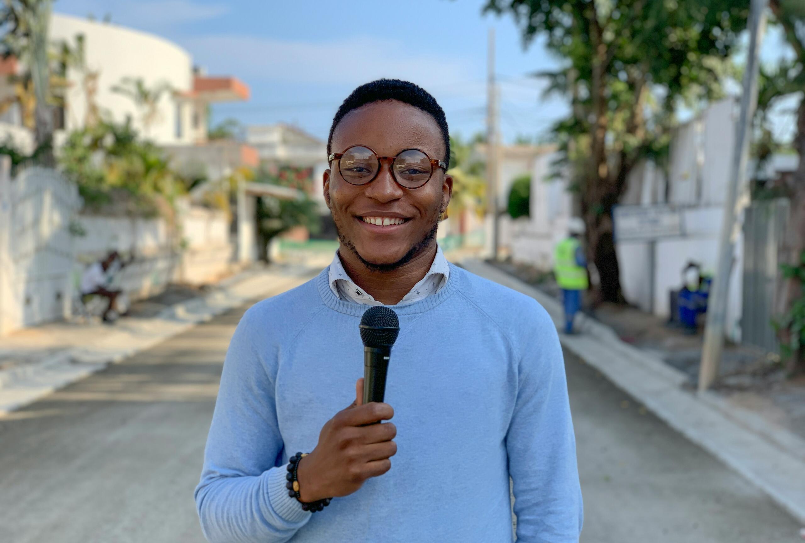 An image of a man with a microphone in a street setting.