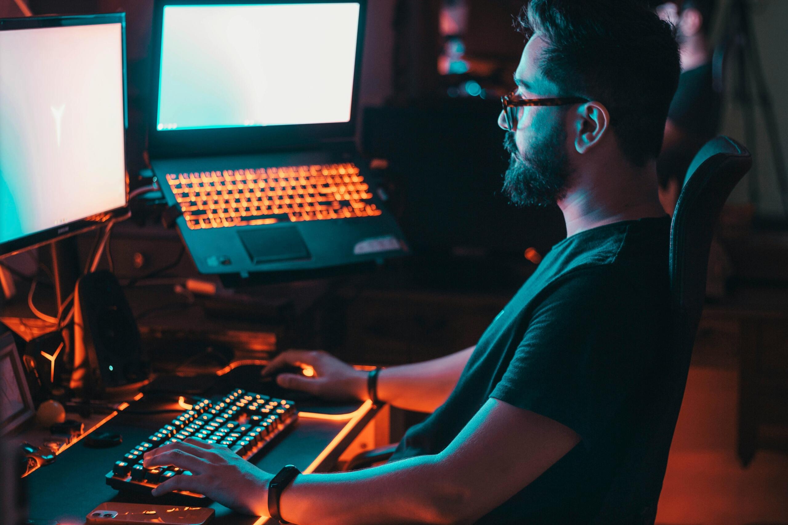 Man working on a laptop with another laptop open on the side