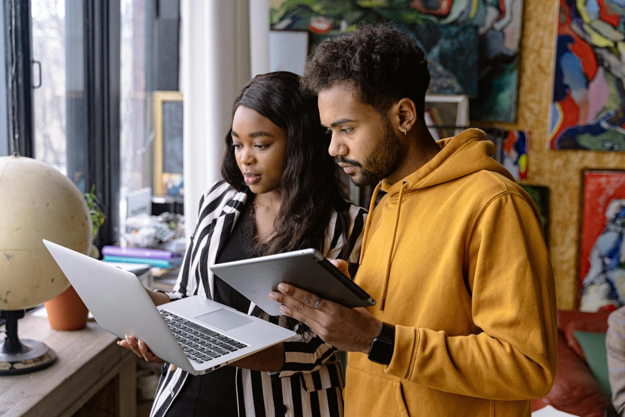 a man holding a tablet and a woman holding a laptop