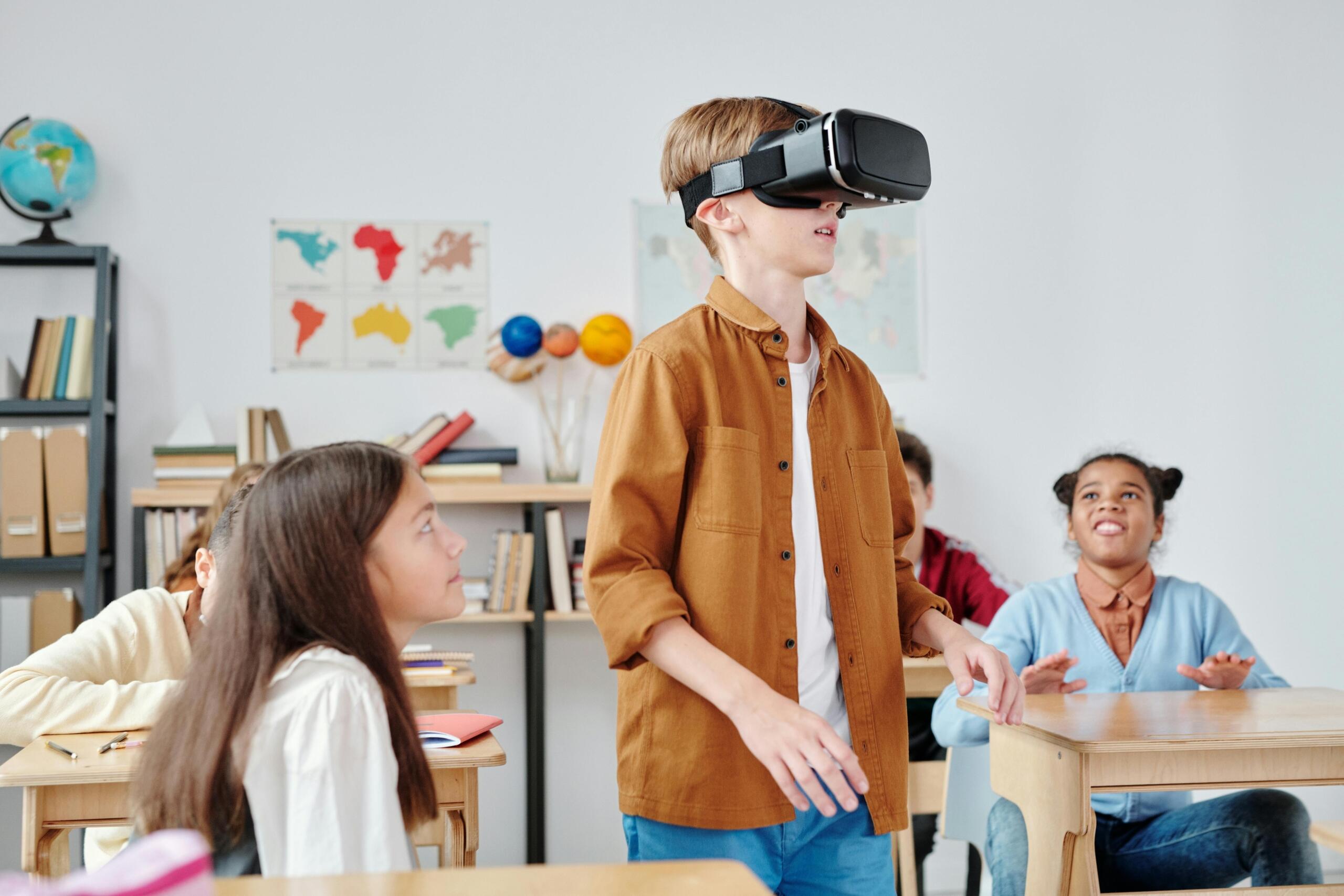 boy in a classroom wearing a virtual reality headset while his classmates look on