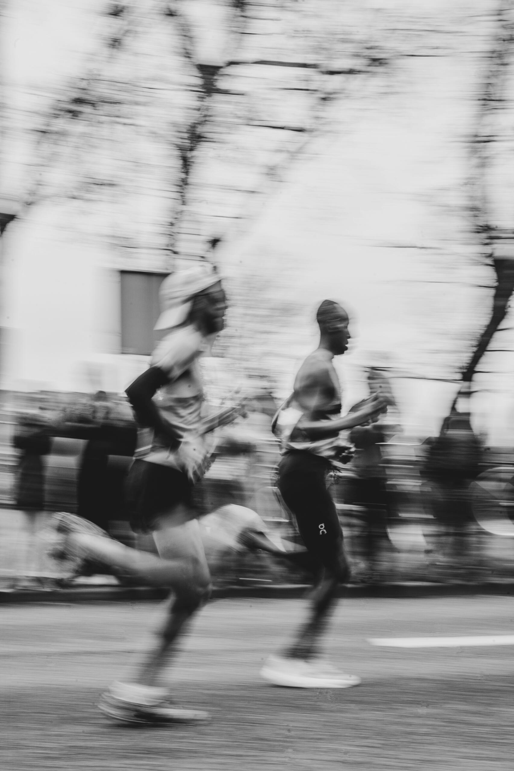 A blurred black and white image of runners in seeming slow motion.