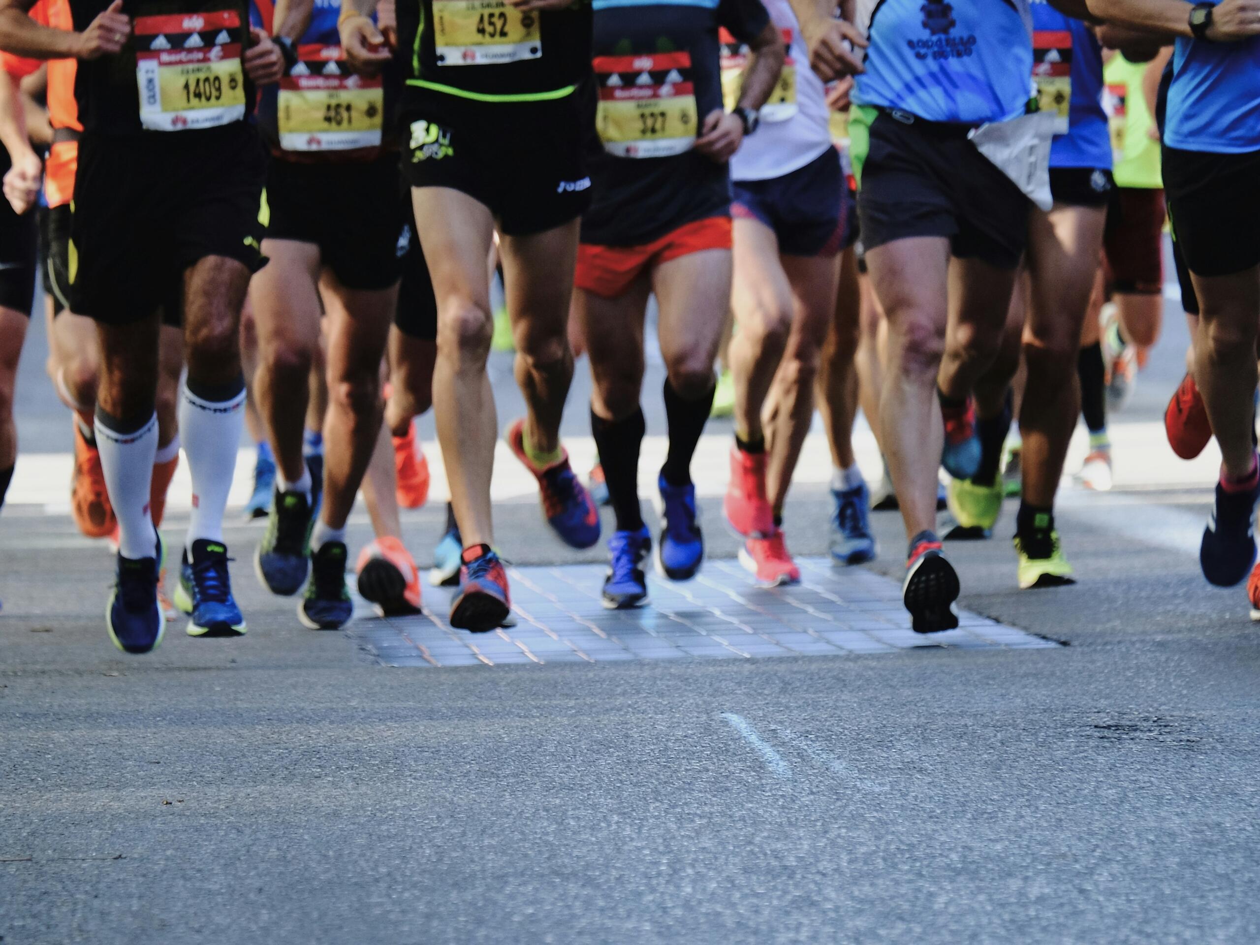 An image of the legs of a group of road runners starting a race.