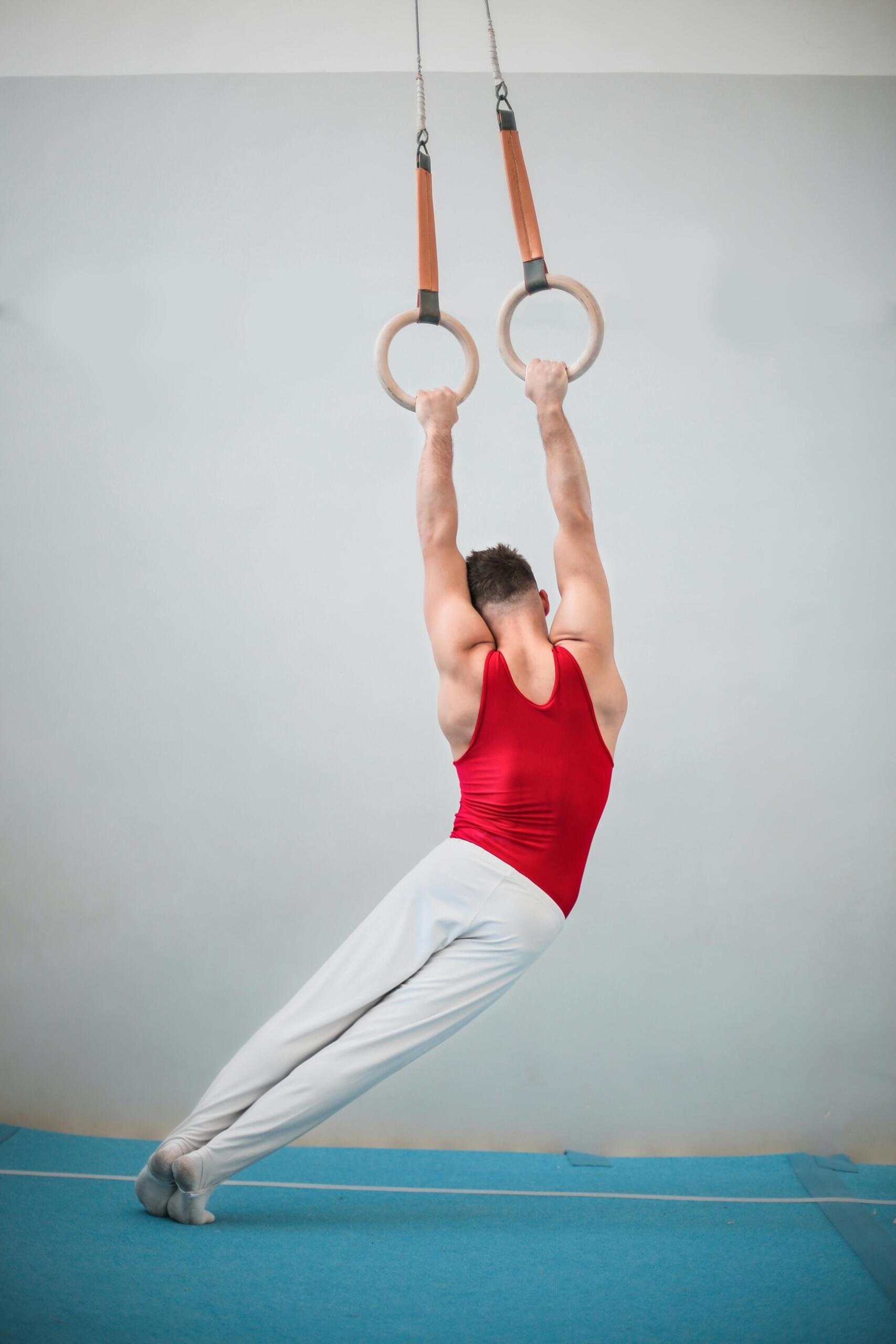A male gymnast swings on apparatus.
