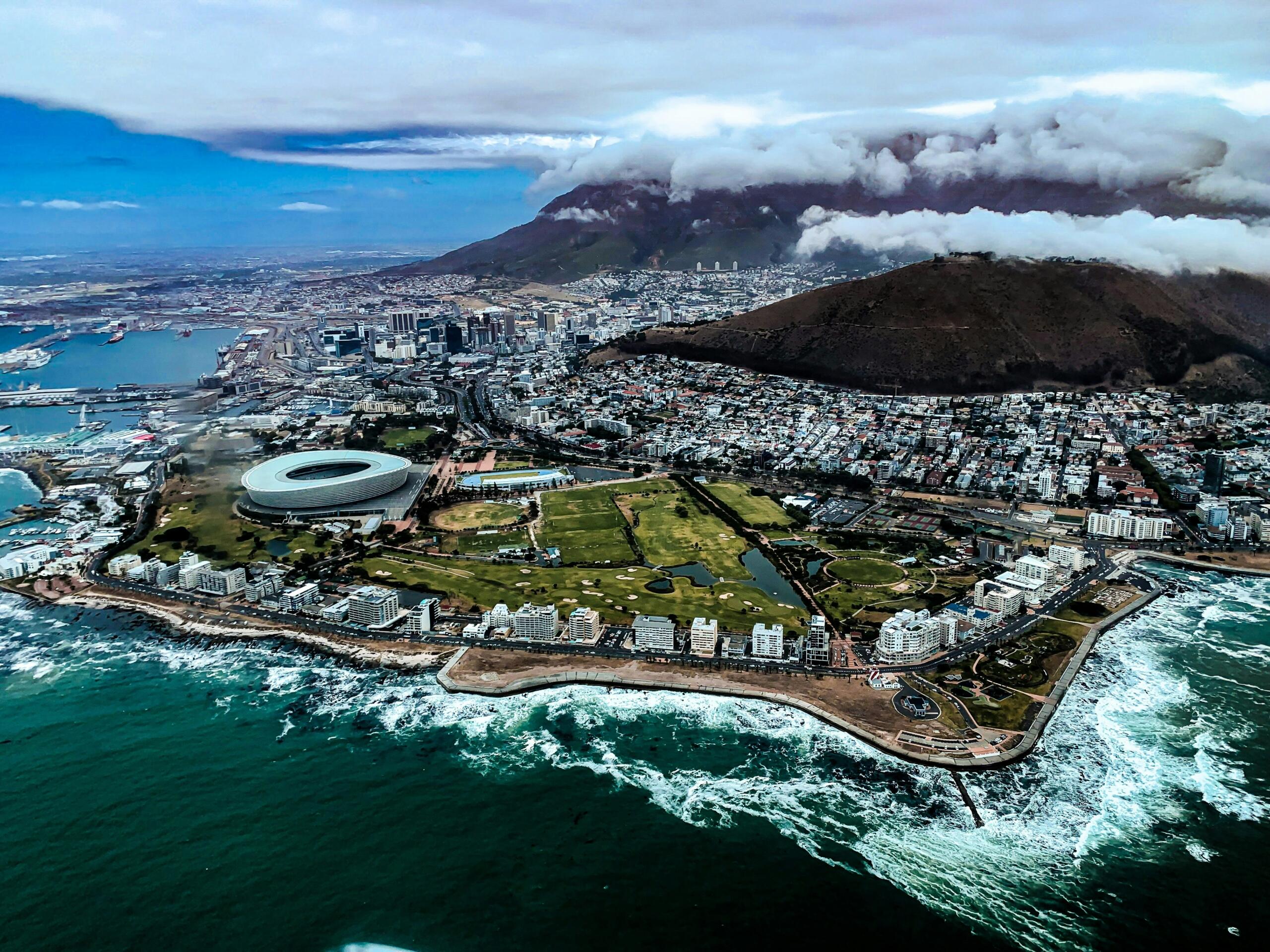 An aerial view of Cape Town including the ocean and Table Mountain.
