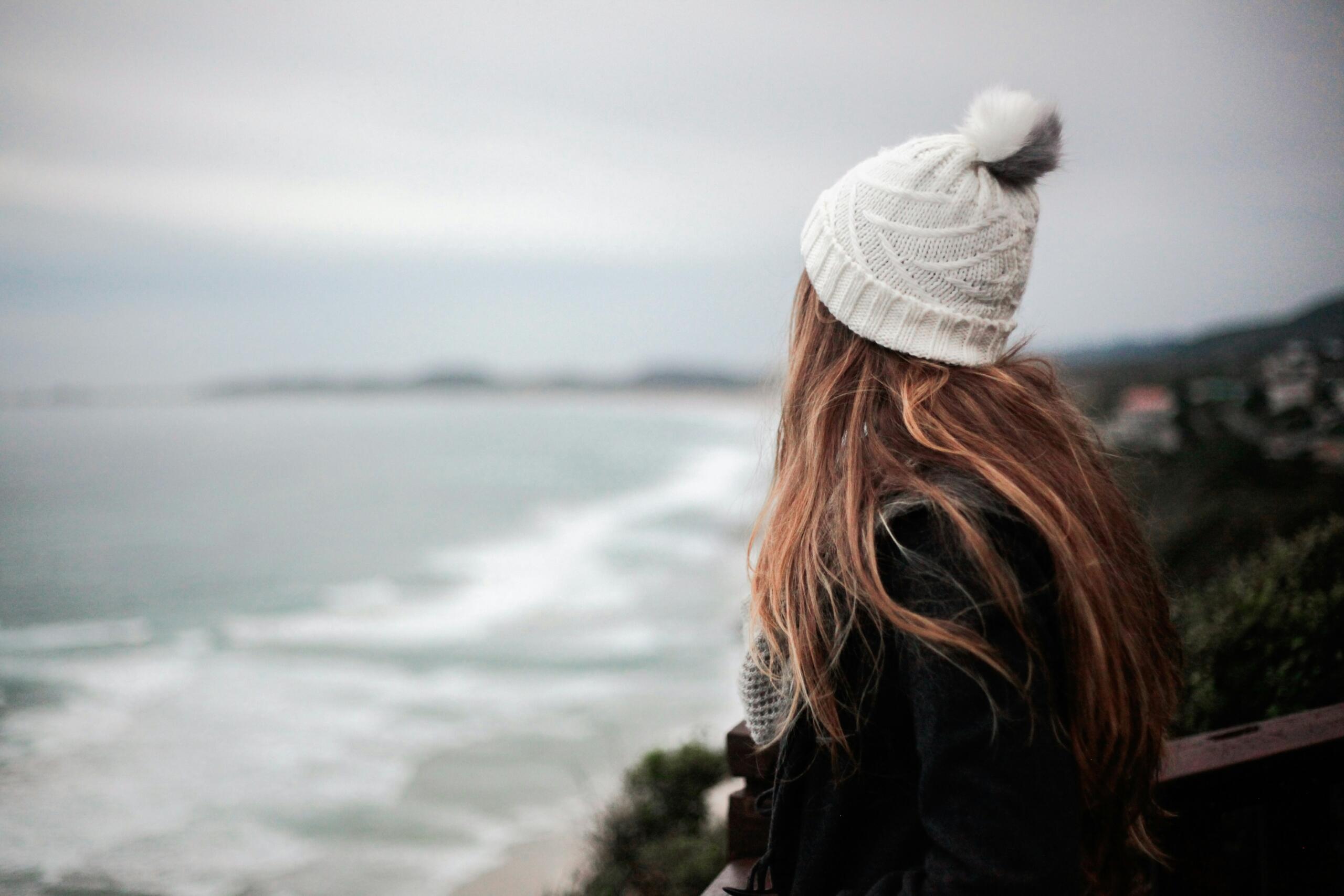 A woman wrapped up in winter woolies admires the ocean.