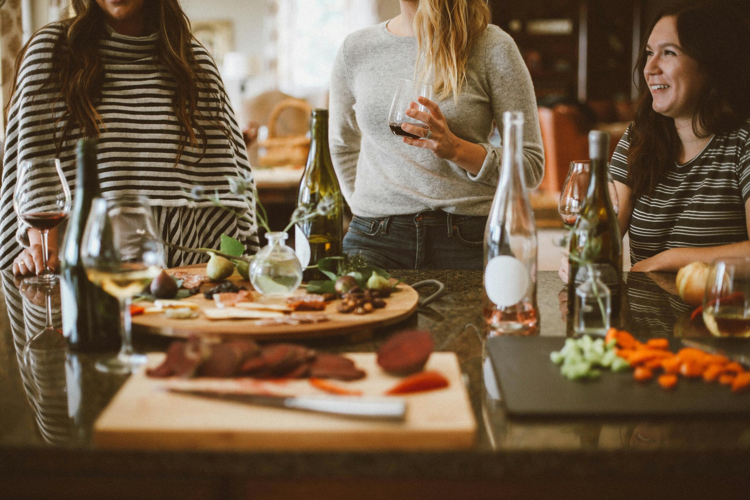 An image of friends around a kitchen counter preparing a meal together.