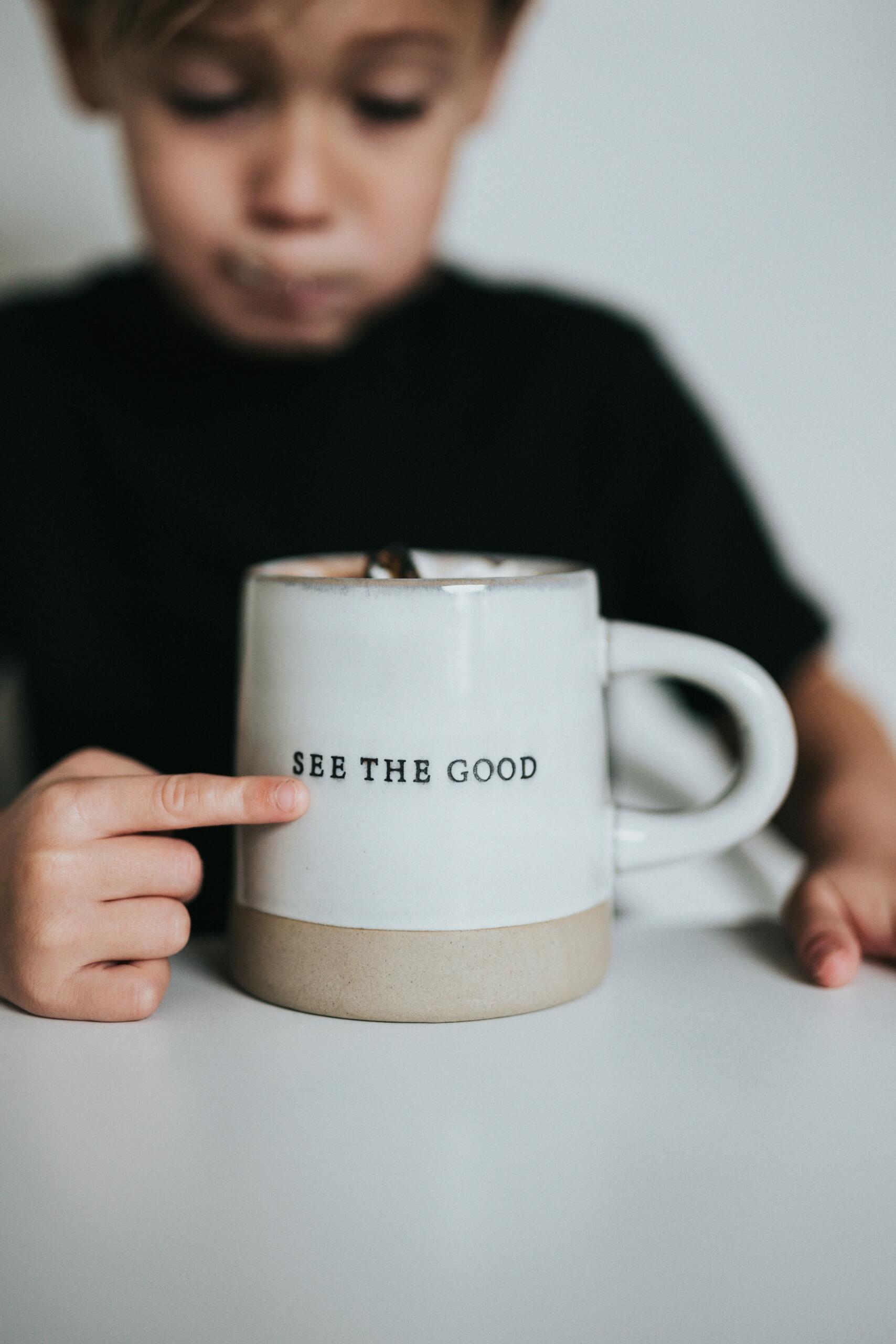 An image of a child and a coffee cup with motivational words on it.