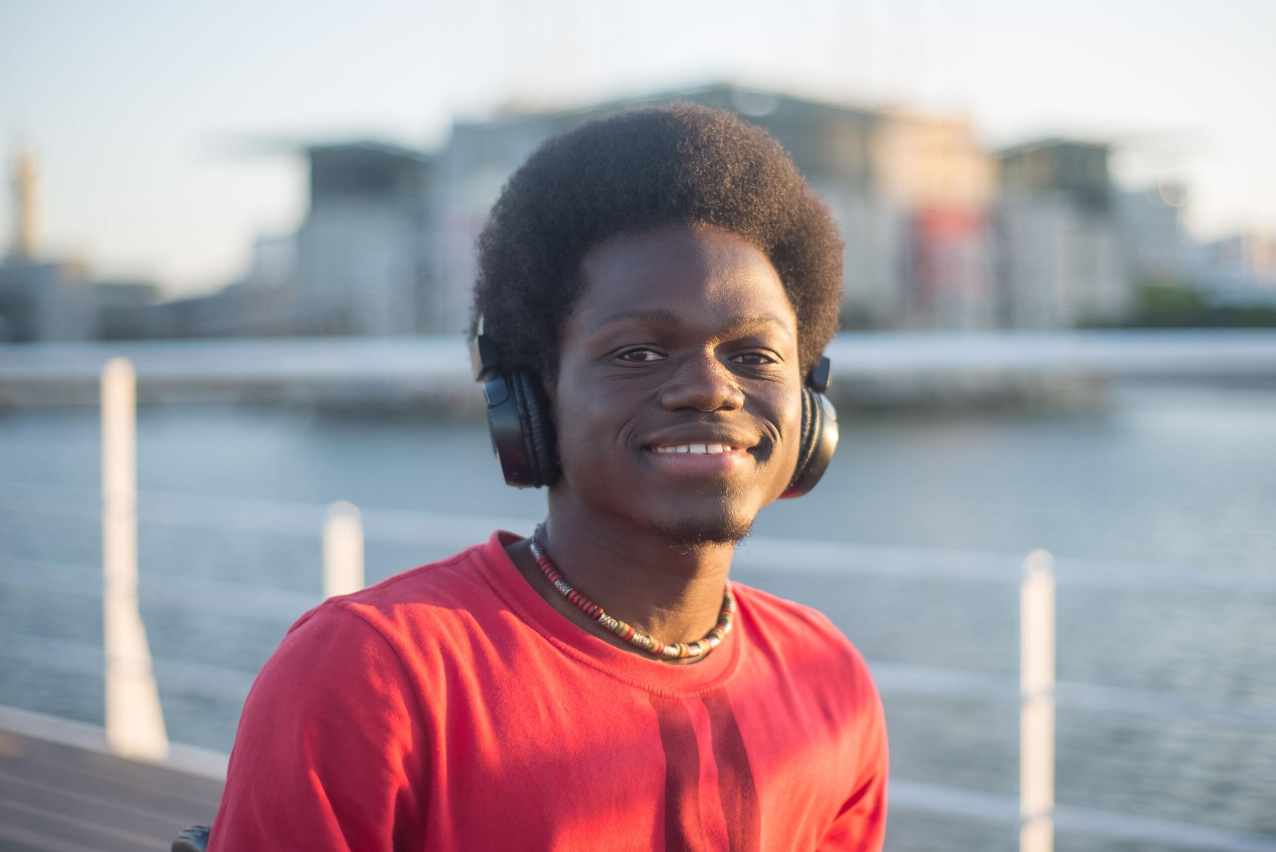 A young, trendy man with headphones in a city scene.
