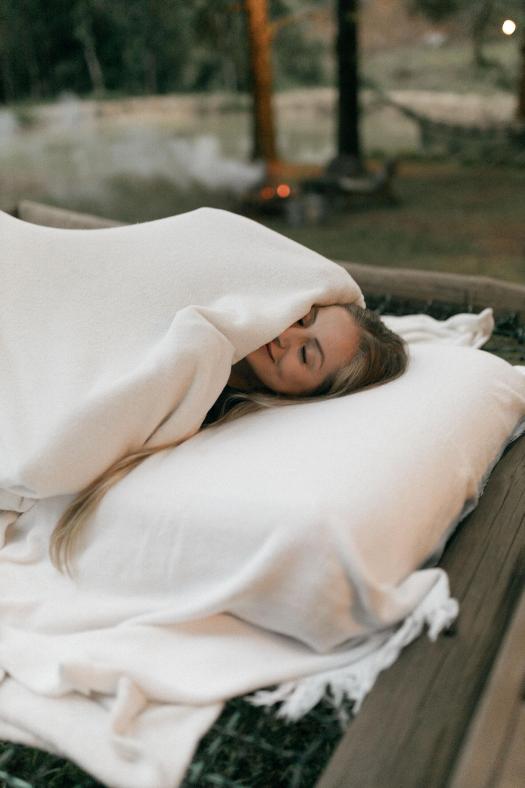 An image of a woman resting in a cosy bed outdoors.