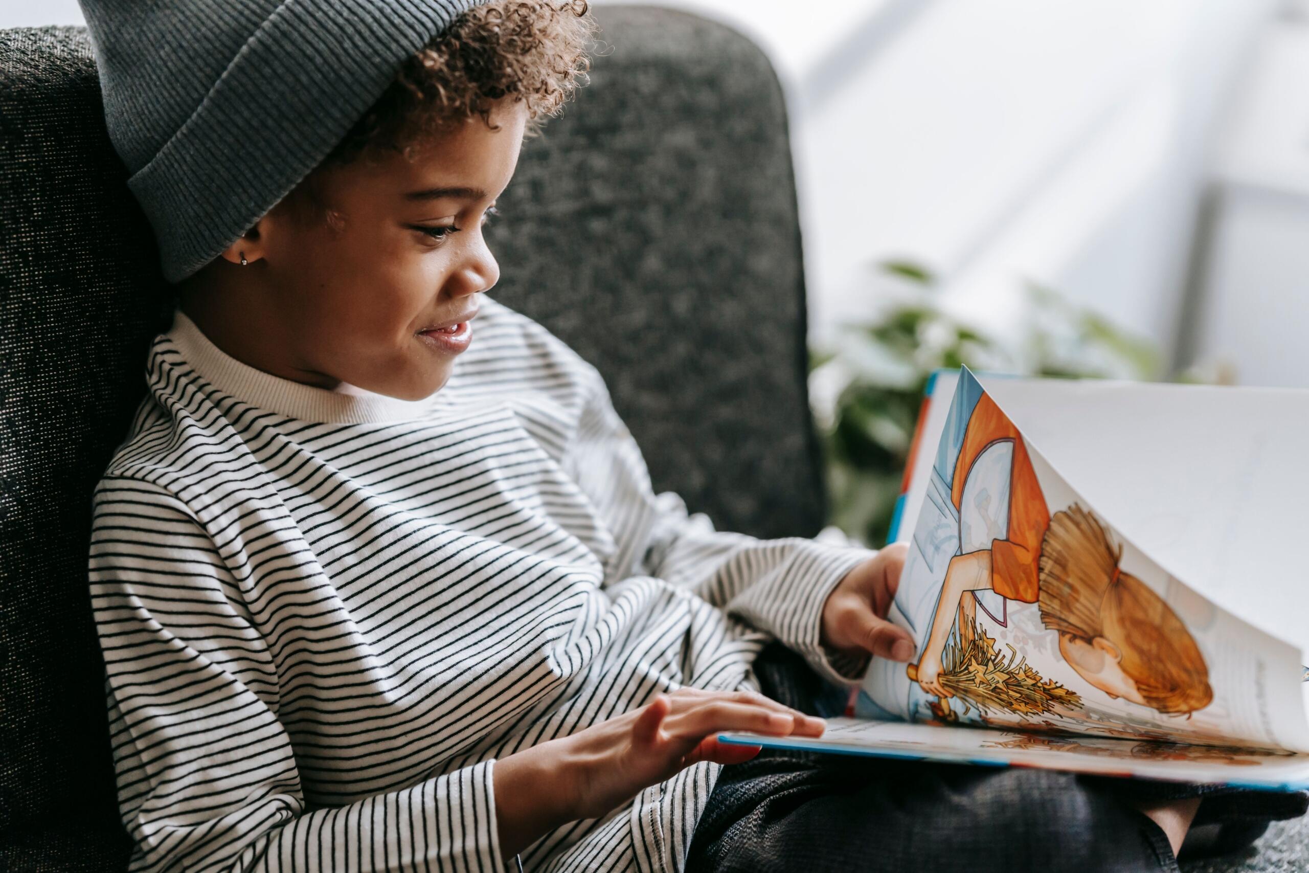 young child sitting on a couch paging through a picture book