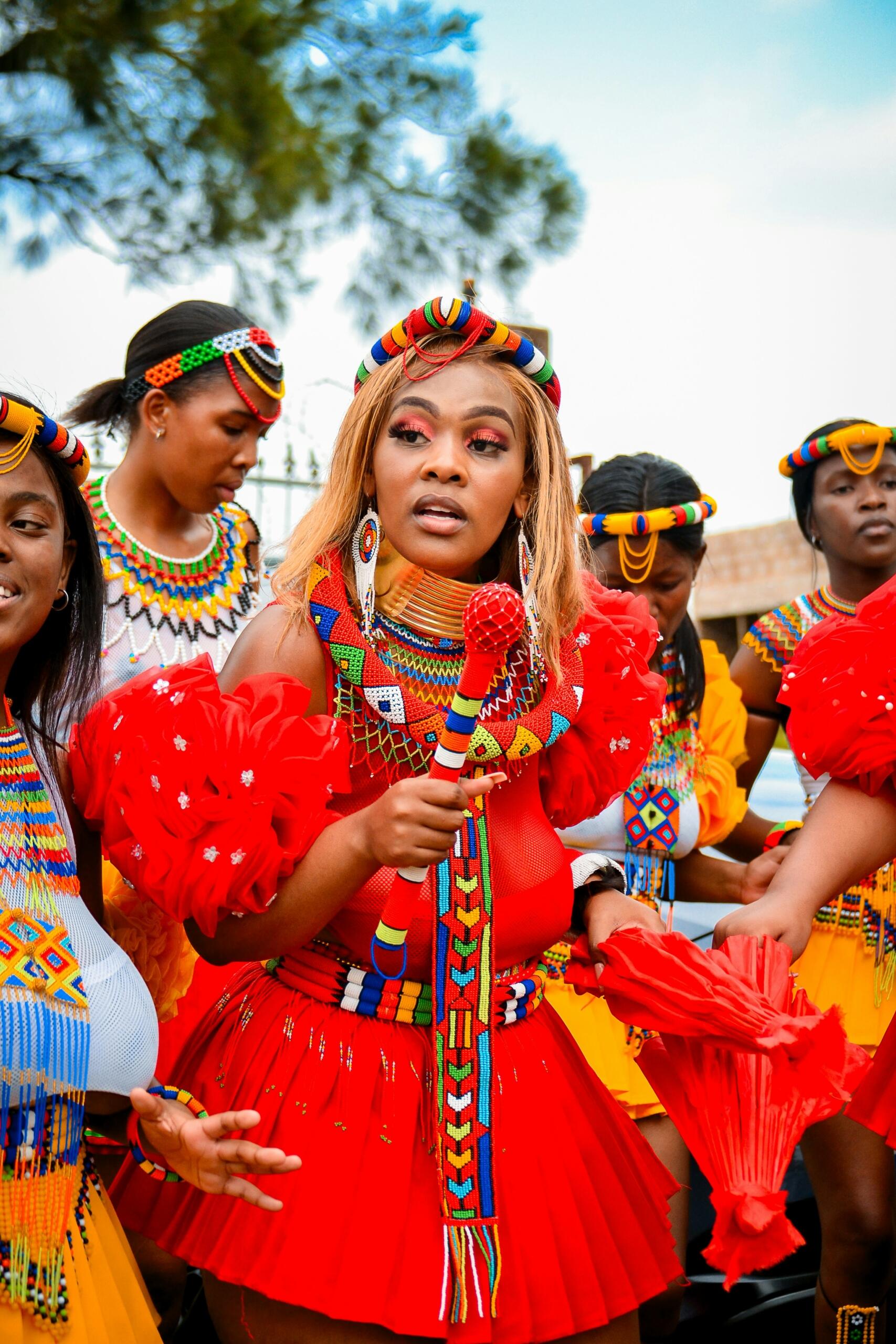 South African women in colourful traditional Zulu inspired clothing and beadwork taking part in a cultural celebration.