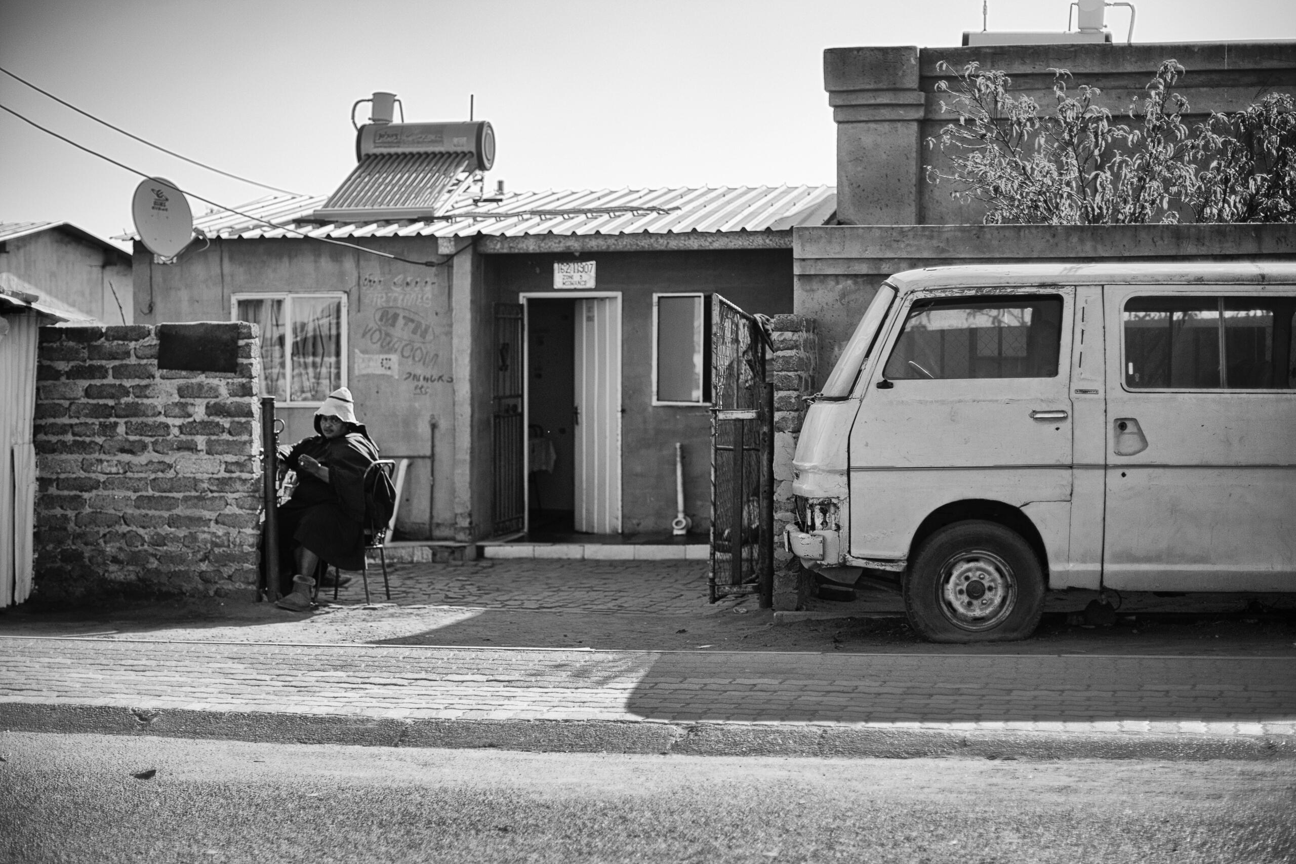 Typical Soweto residential street with modest homes, a parked minibus and a resident outside.