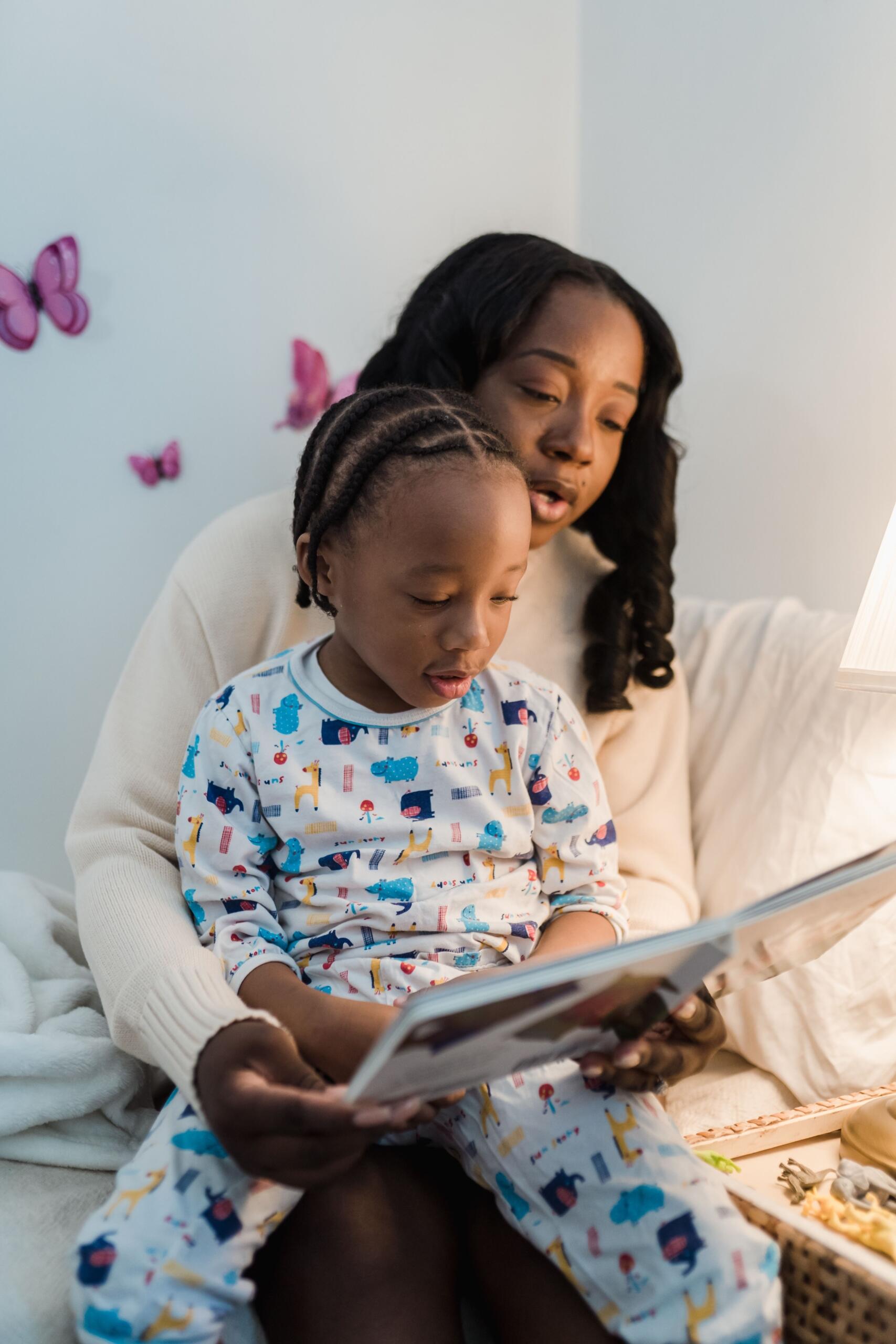 young boy sitting on mom's lap as she reads a story to him