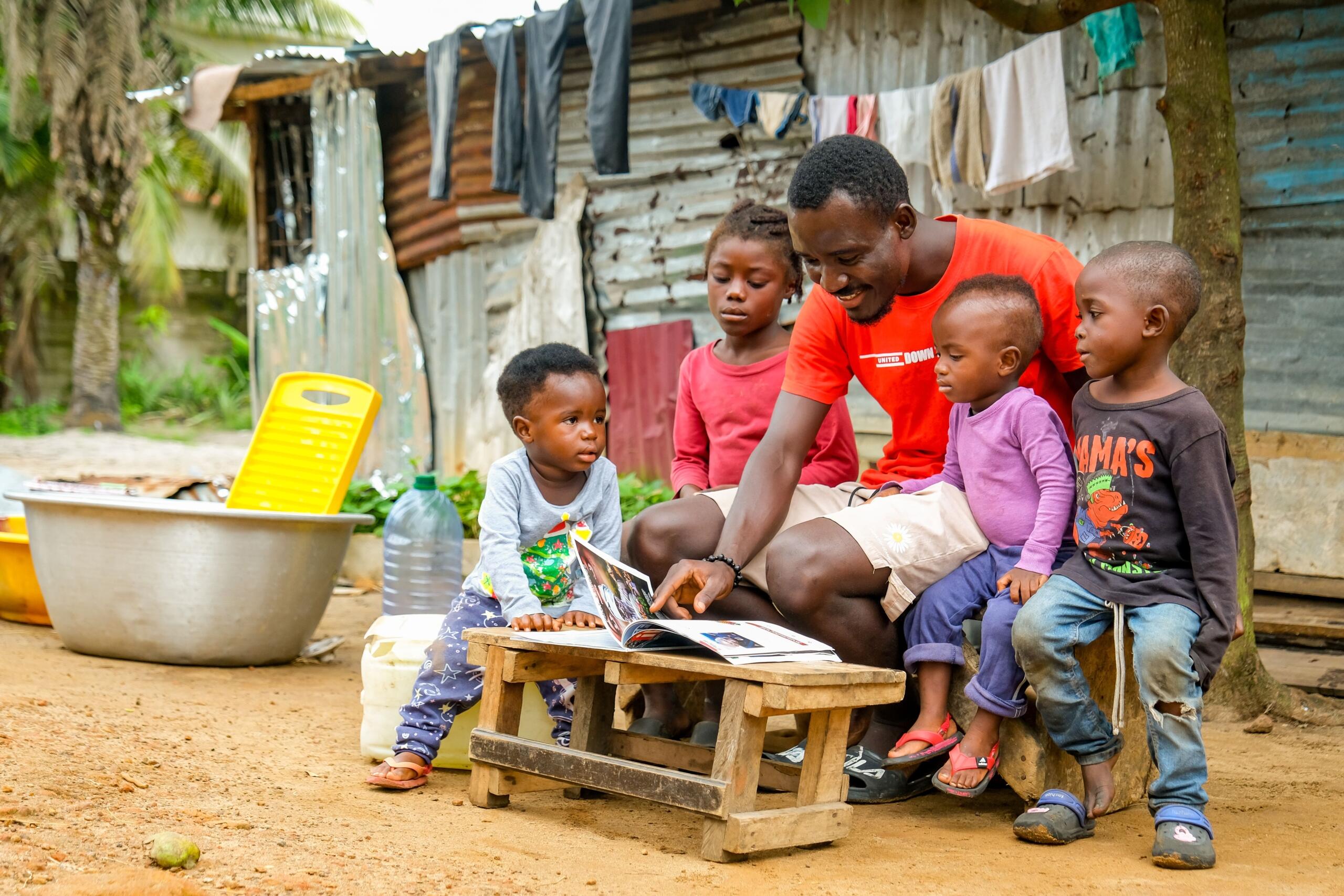 An image of an African man sharing a story with a group of children.