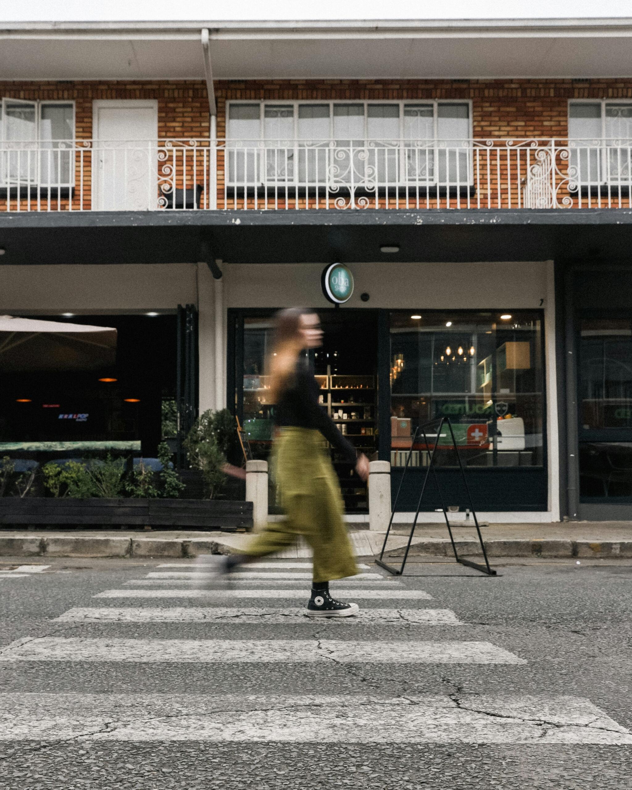 An image of person in fast-motion crossing the road at a pedestrian crossing.