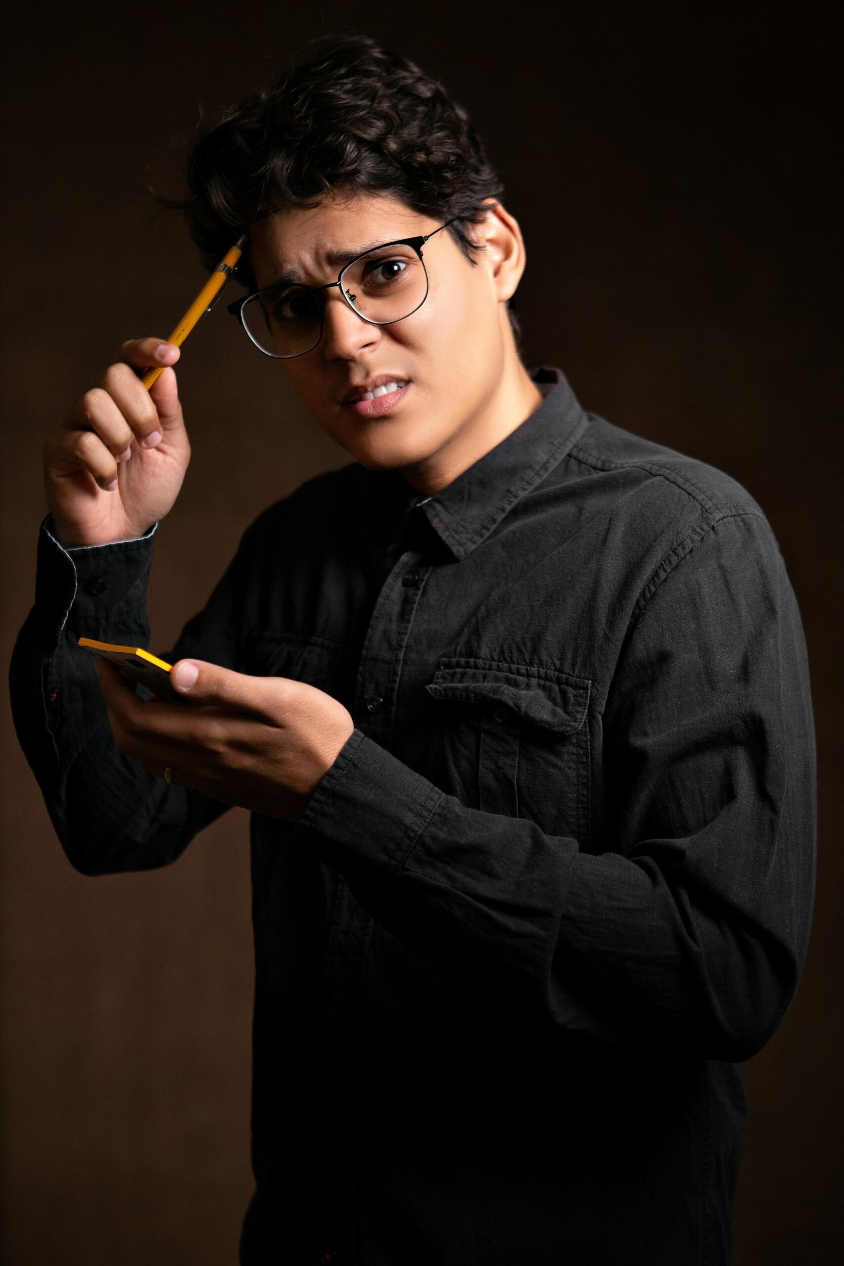 Young man looking at his smartphone while holding a pair of glasses